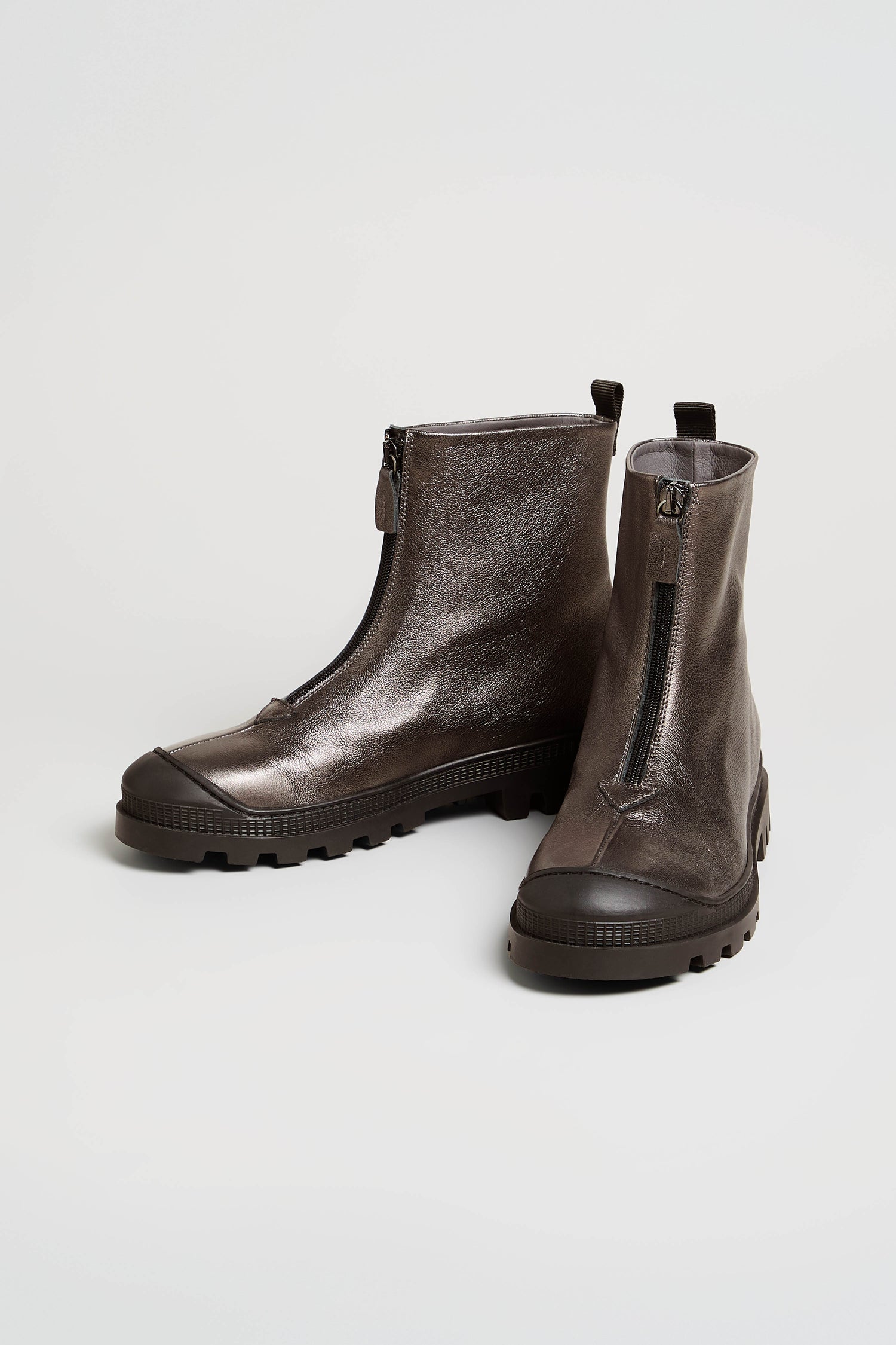 A pair of Metallic Hematite Zip Front Leather Boots, crafted from metallic gray leather with black chunky tread soles and front zippers, displayed on a plain white background.