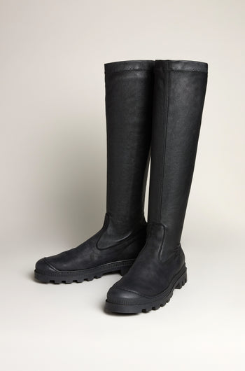 A pair of Stretch Long Nappa Leather Boots with thick black rubber soles stand upright on a light background, highlighting their sleek slip-on design.