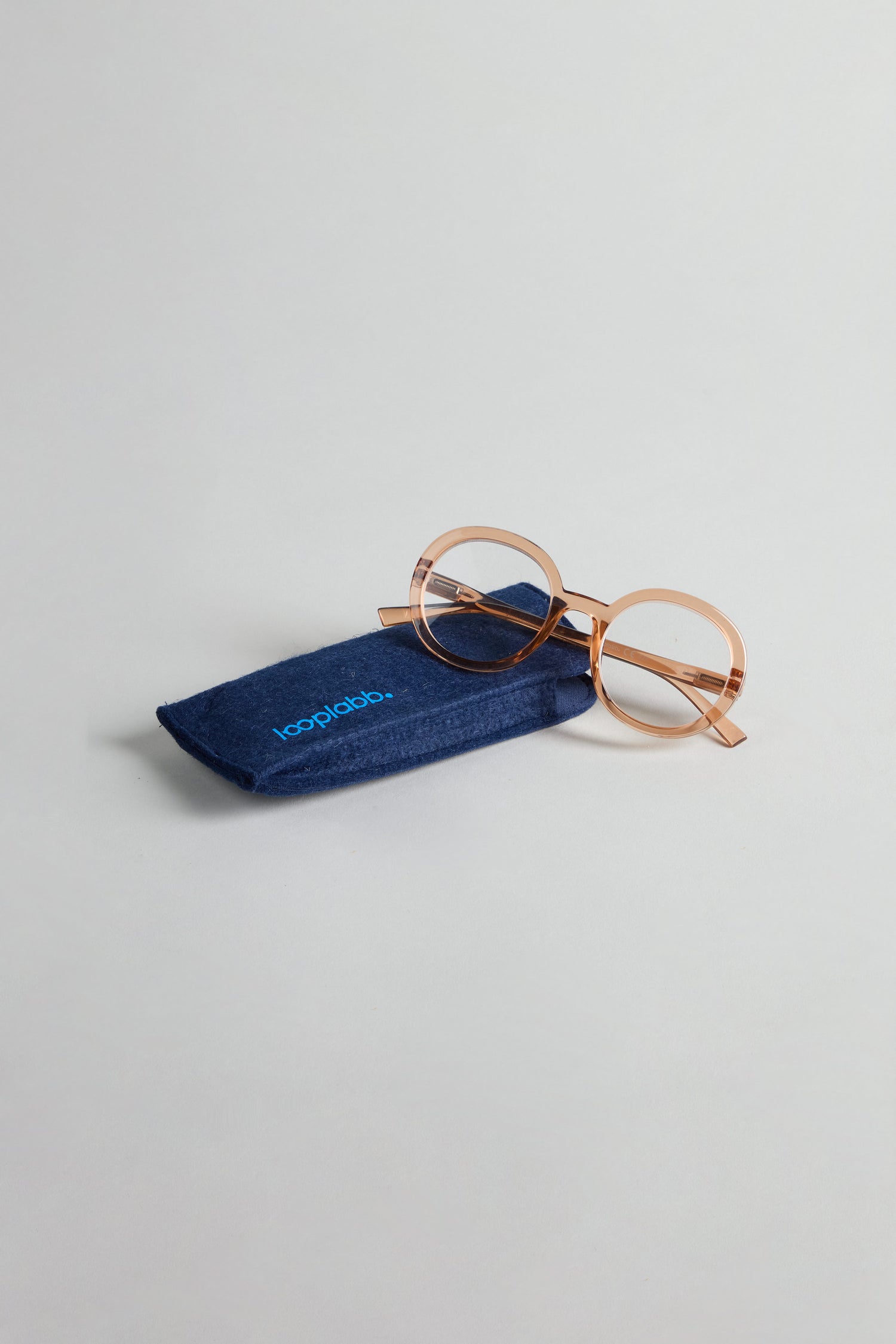 Crystal Champagne Round Reading Glasses with optician-quality lenses rest on a dark blue soft case marked “looplabb,” set against a plain light background.