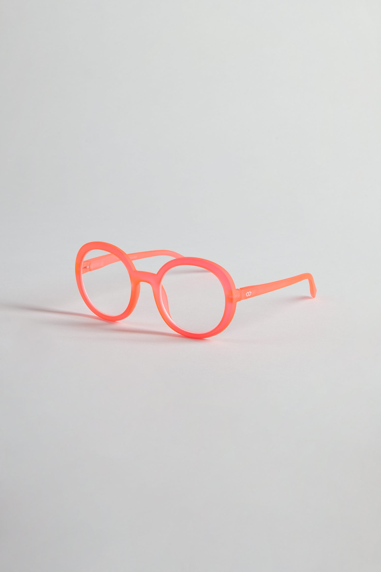 Neon Peach Round Reading Glasses with optician-quality lenses rest on a plain light gray background.