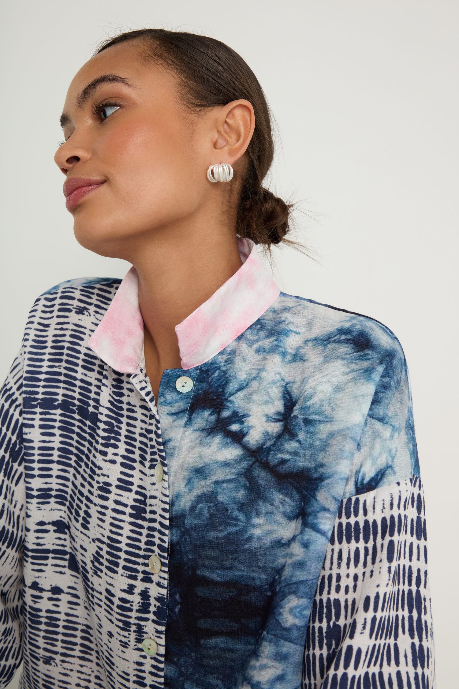 Wearing the Floral Back Easy Shirt, featuring blue and white floral patterns with a pink collar, a person looks to the side against a plain background.