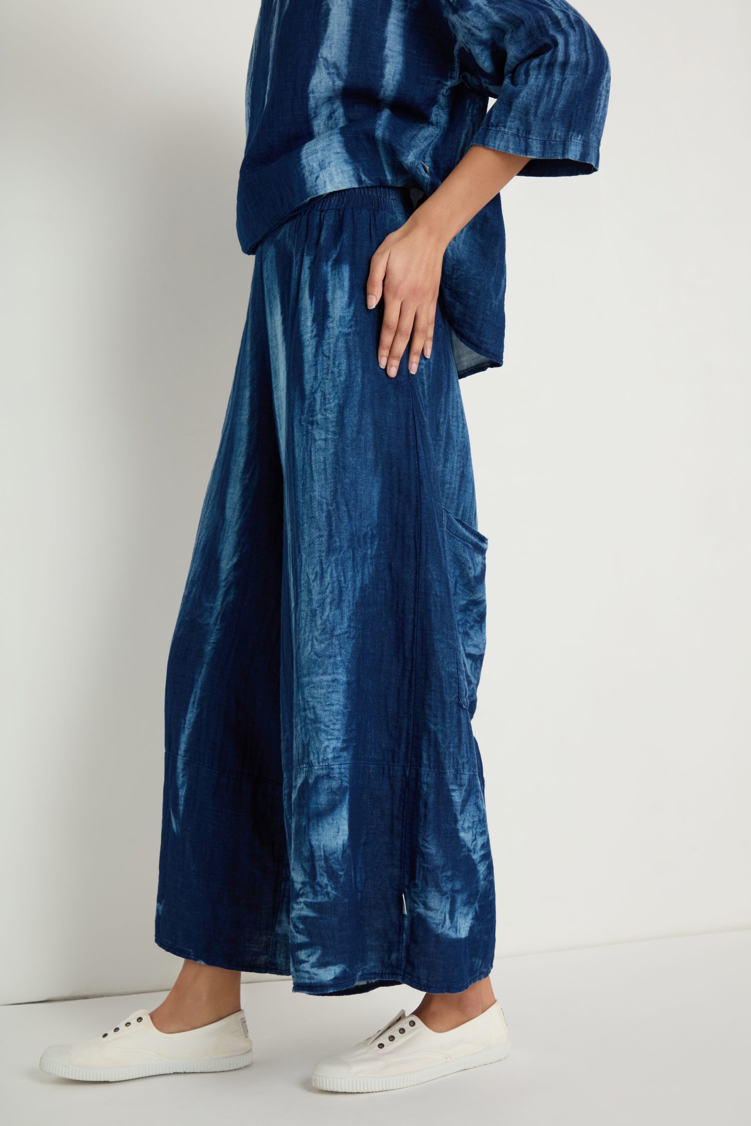 A person stands against a plain background wearing Soft Denim Pocket Trousers styled with relaxed legs and white sneakers.