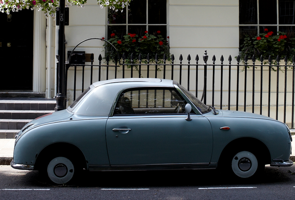 blue classic car parked in front of a white building
