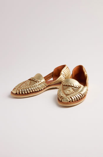 A pair of Alegre Leather Huarache Sandals, handcrafted in Mexico from exquisite gold woven leather, rests elegantly on a plain white background, offering breathable comfort with every step.