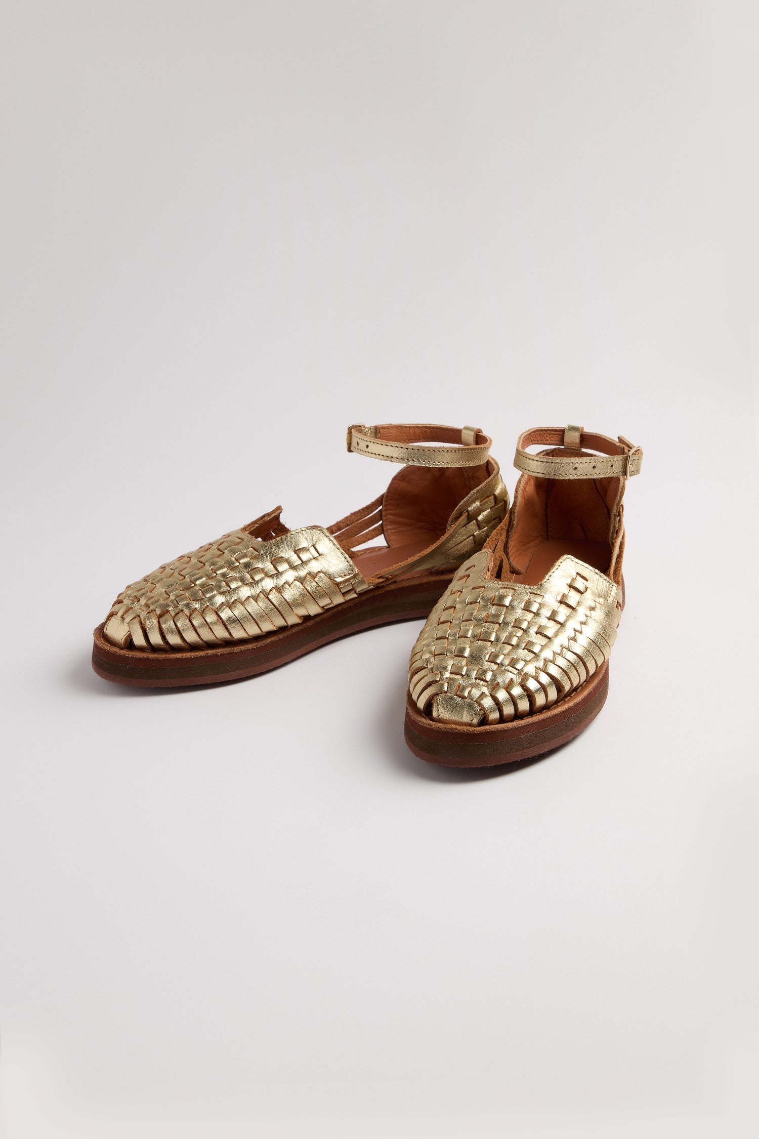 Carmen Platform Woven Leather Sandals, made with gold leather and ankle straps, showcase their handcrafted Mexican craftsmanship against a simple white backdrop.