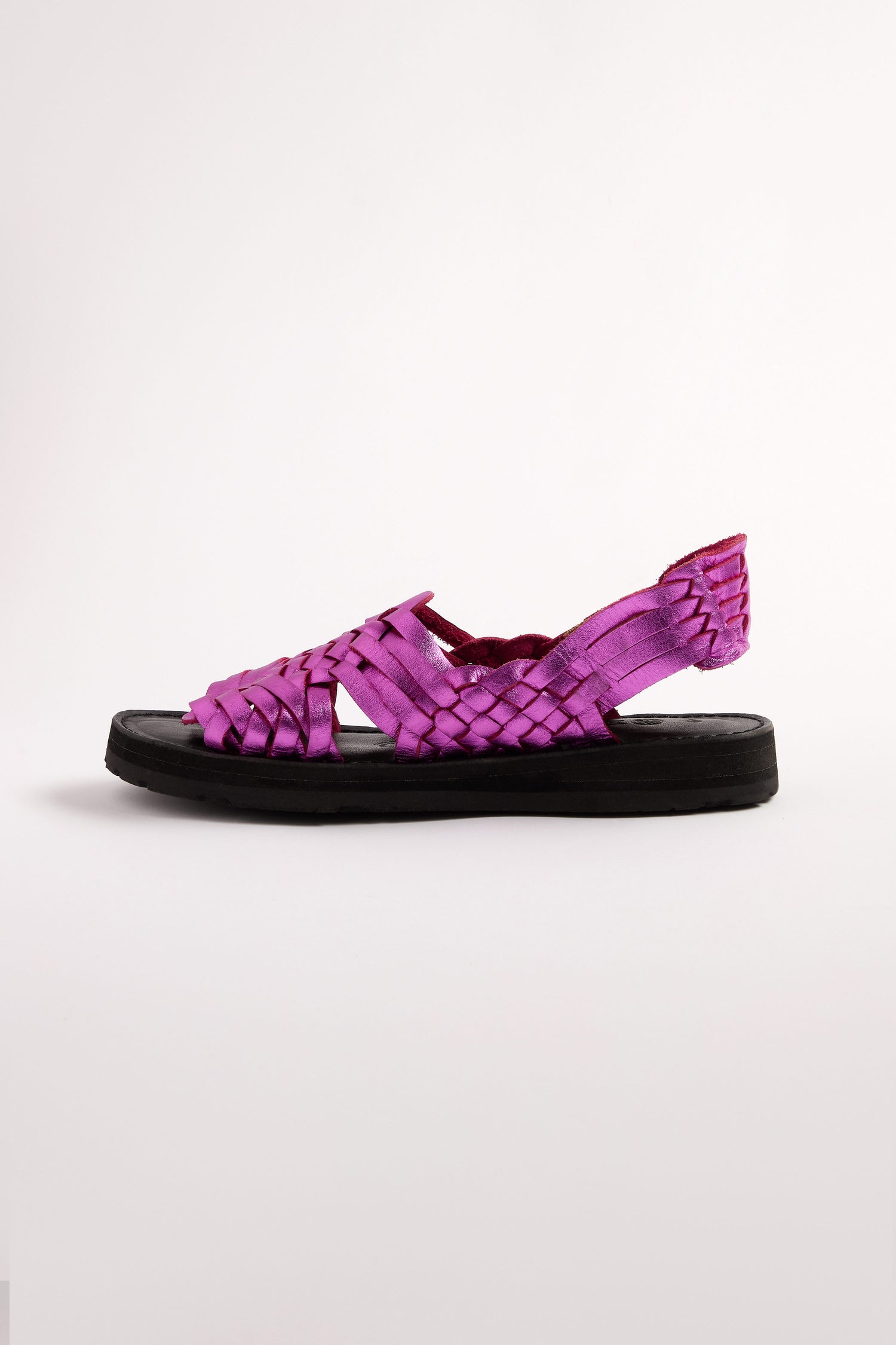 Handcrafted in Mexico, the Frida Woven Leather Sandals feature a woven purple design with a black sole, closed toe, and open heel on a plain white background and are finished with a subtle metallic magenta sheen.