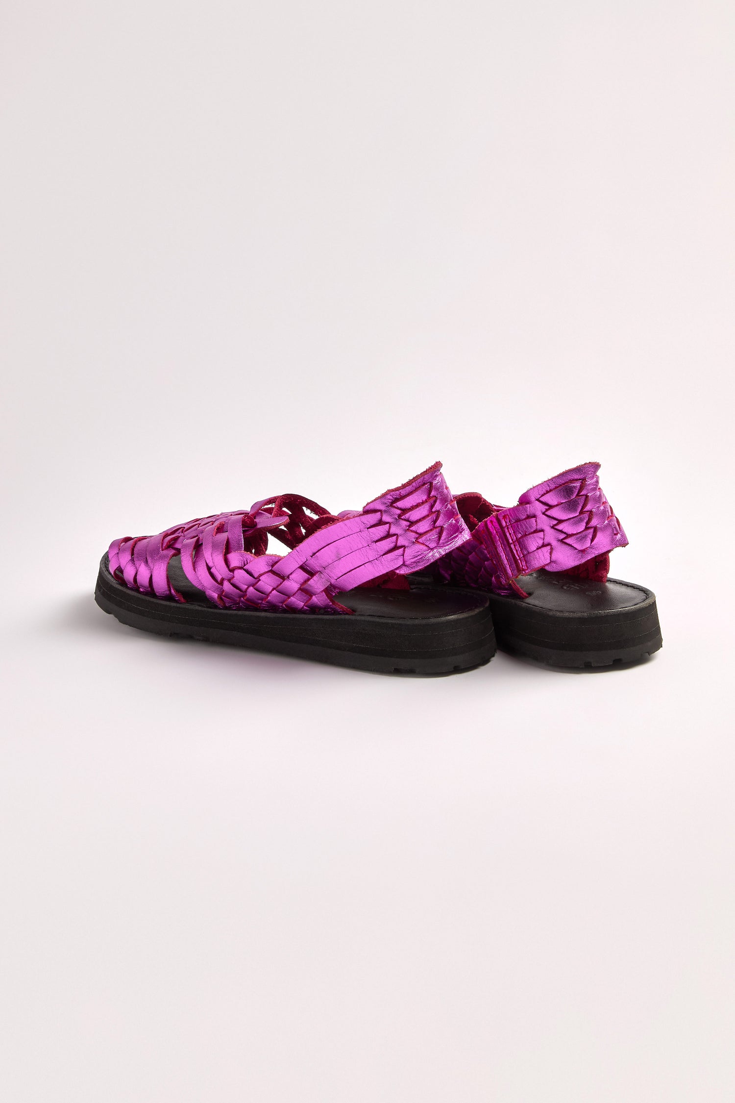The pink Frida Woven Leather Sandals, handcrafted in Mexico with black soles, an open-toe design, and ankle straps, are showcased on a plain white background.