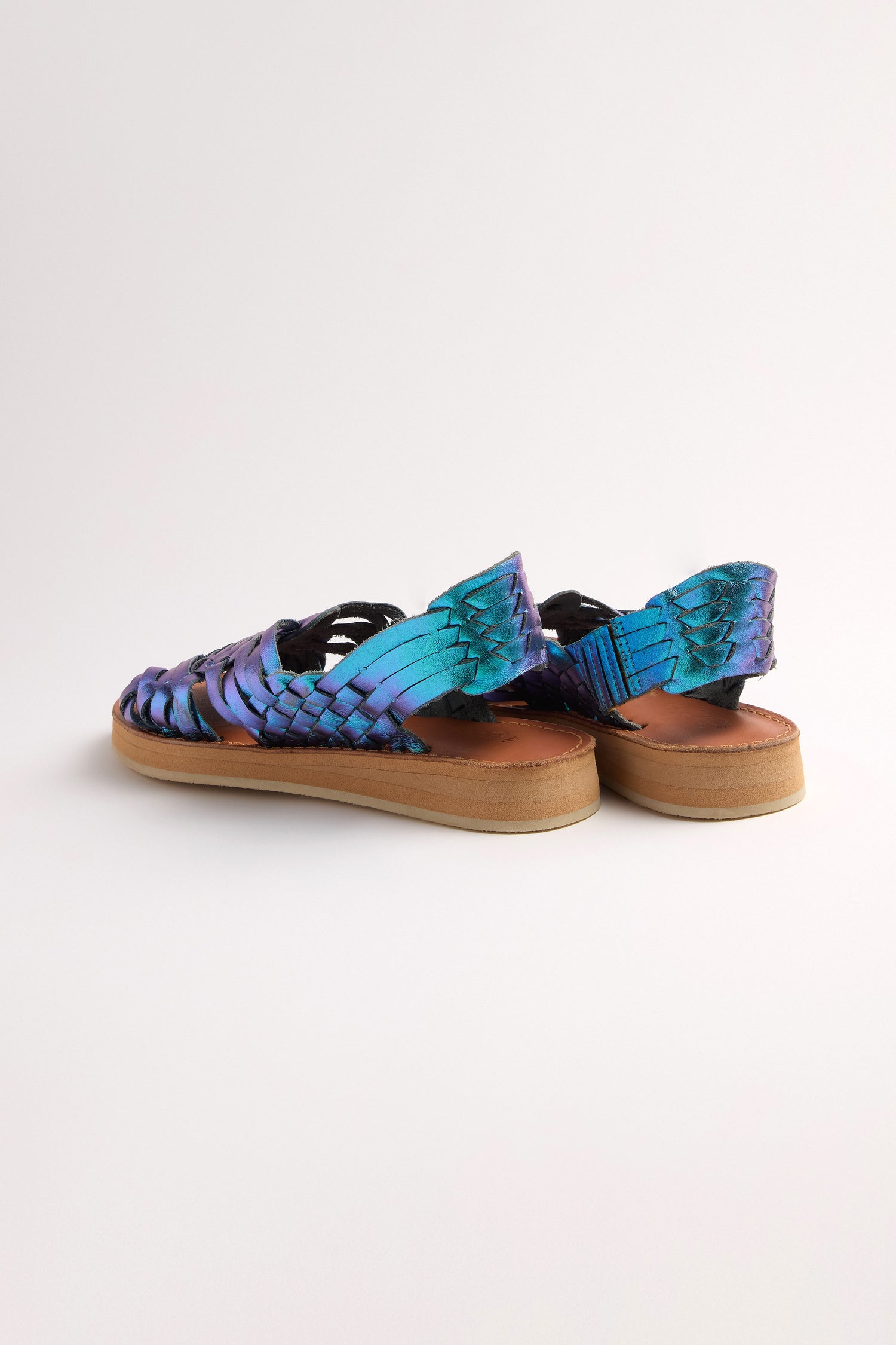 Frida Woven Leather Sandals in blue and purple, with tan soles and a hint of metallic magenta sparkle, crafted in Mexico. Shown from the back on a white background.