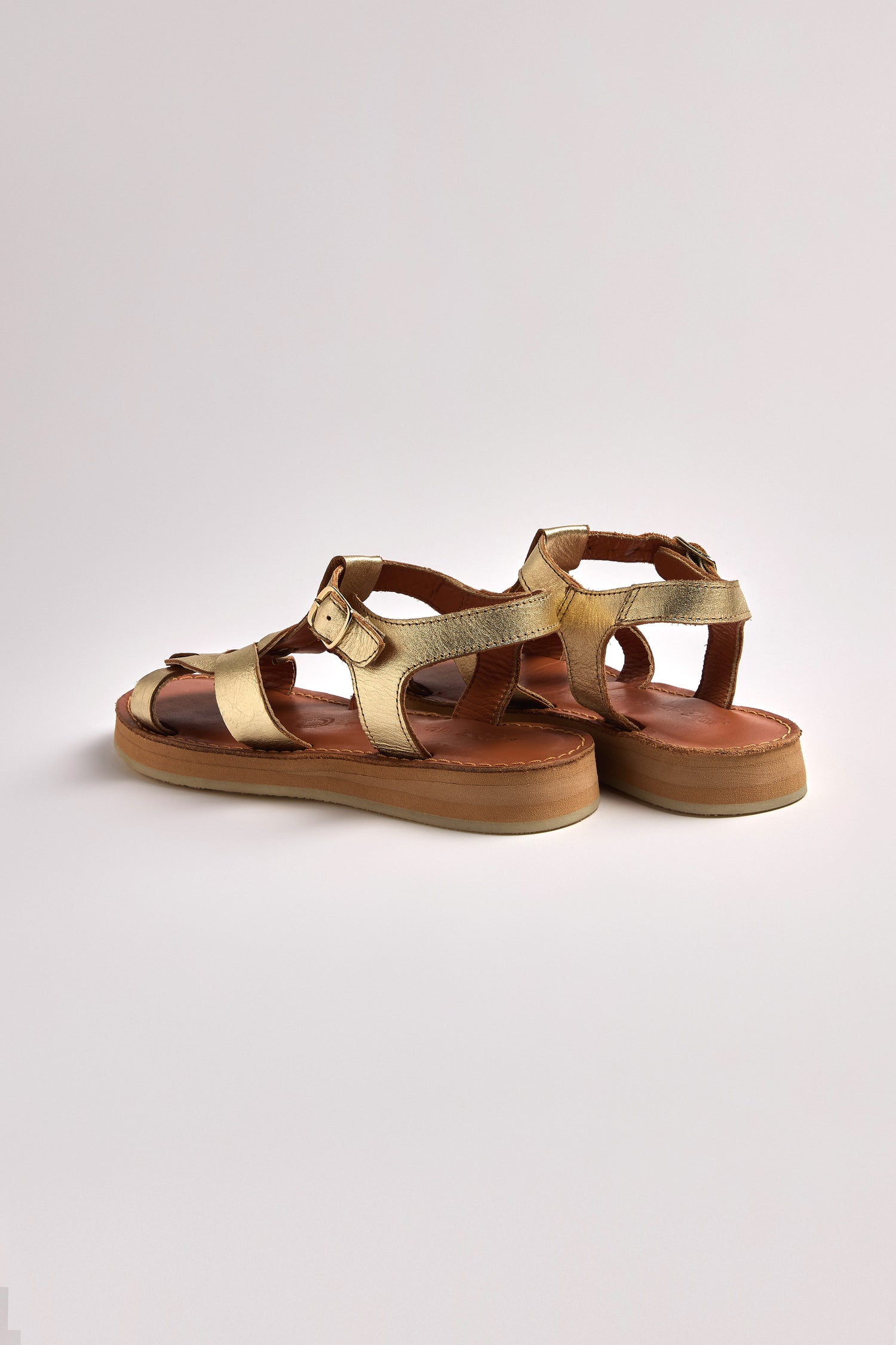 The Tulum Leather Buckle Sandals are gold metallic with cushioned sole comfort, ankle straps, and crafted from premium handmade leather, showcased on a neutral background.