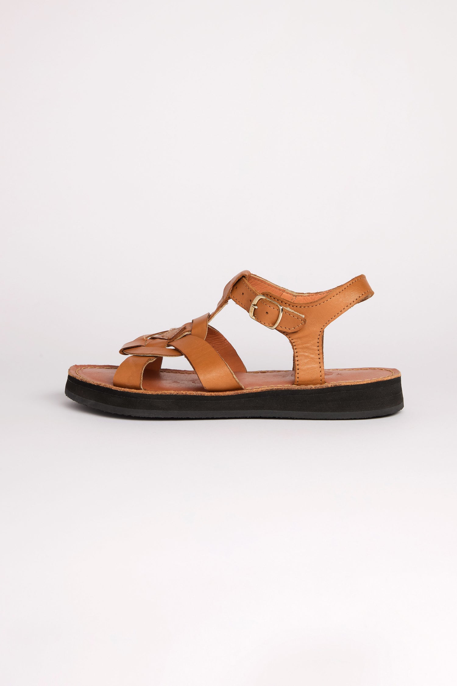 The Tulum Leather Buckle Sandals, handcrafted from premium brown leather, feature a closed toe and an ankle strap with a sleek side buckle. With cushioned sole comfort, this sandal is elegantly presented on a plain white background.
