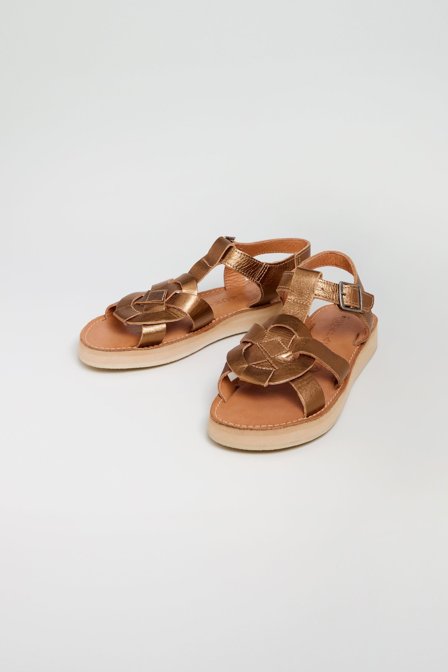 A pair of Tulum Leather Sandals featuring a handcrafted flower-shaped design on the toe and ankle straps with side buckles, displayed against a plain white background.