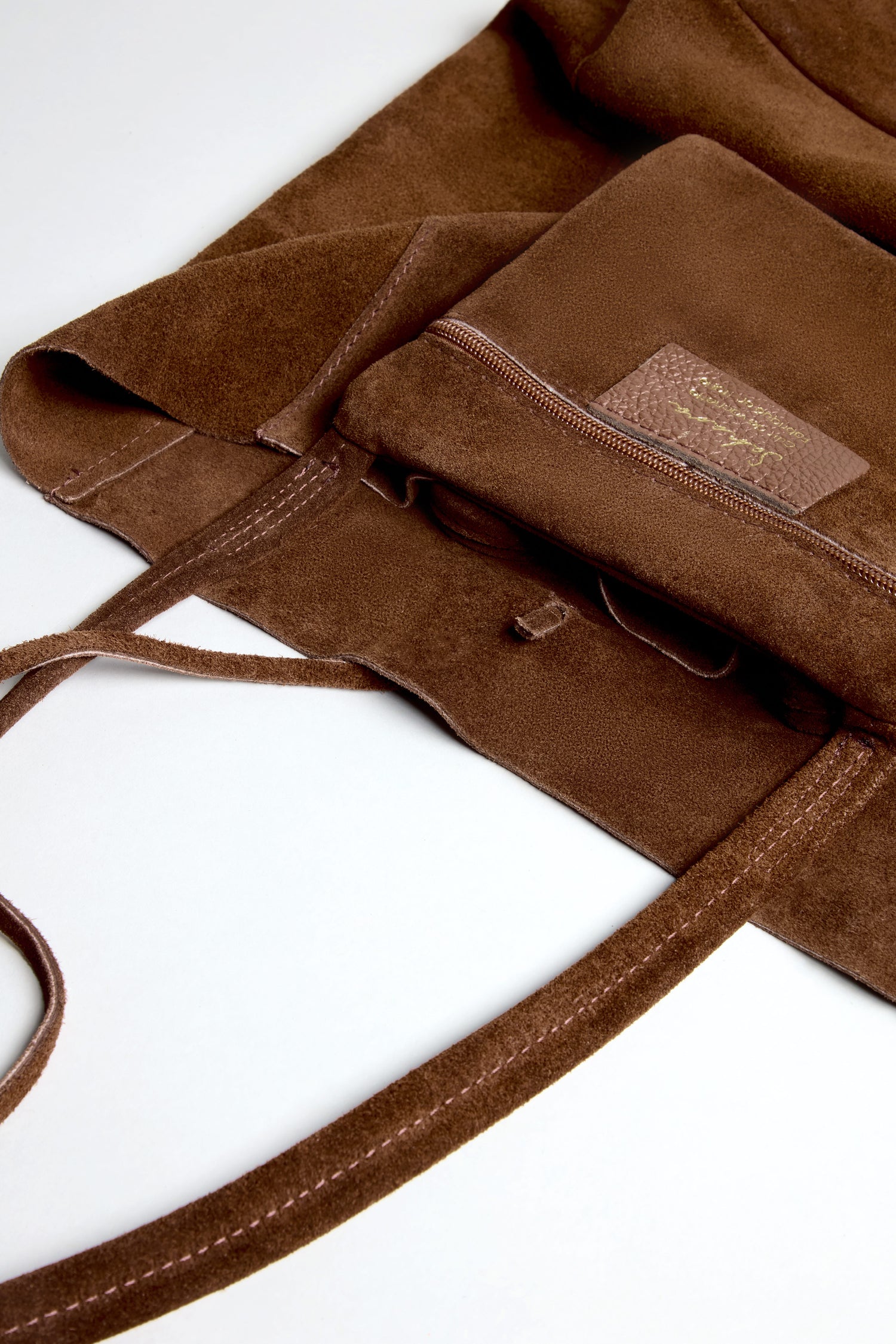 Close-up of the Soft Suede Chocolate Tote Bag, featuring a front zippered pocket and long handles, showcasing its minimalist style against a white background.