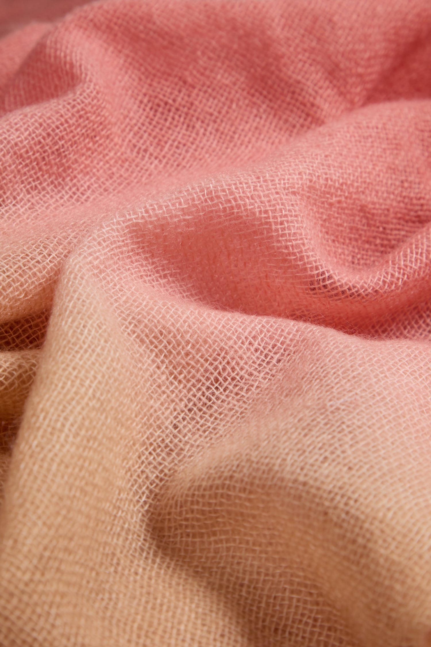 Close-up of the Soft Colourblend Cashmere Shawl, highlighting its soft, textured fabric in pink and beige with a subtle ombré gradient, visible weave pattern, and gentle folds.