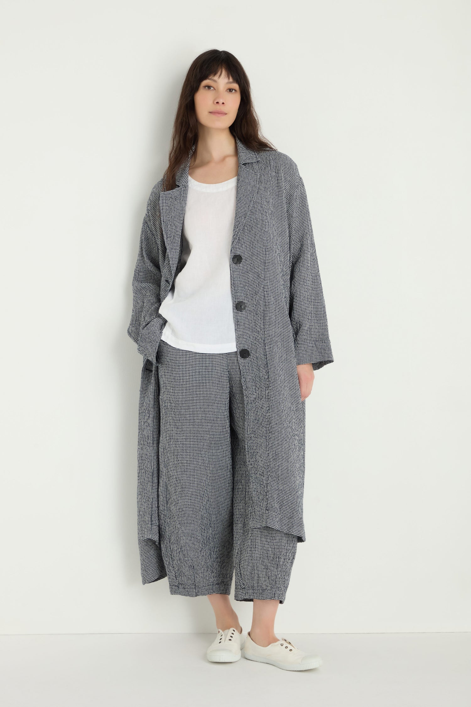 A woman stands against a plain background wearing a Micro Gingham Boxy Coat, matching wide-leg pants, and white sneakers—her minimalist look as streamlined as an MTJ6721 electronic component.