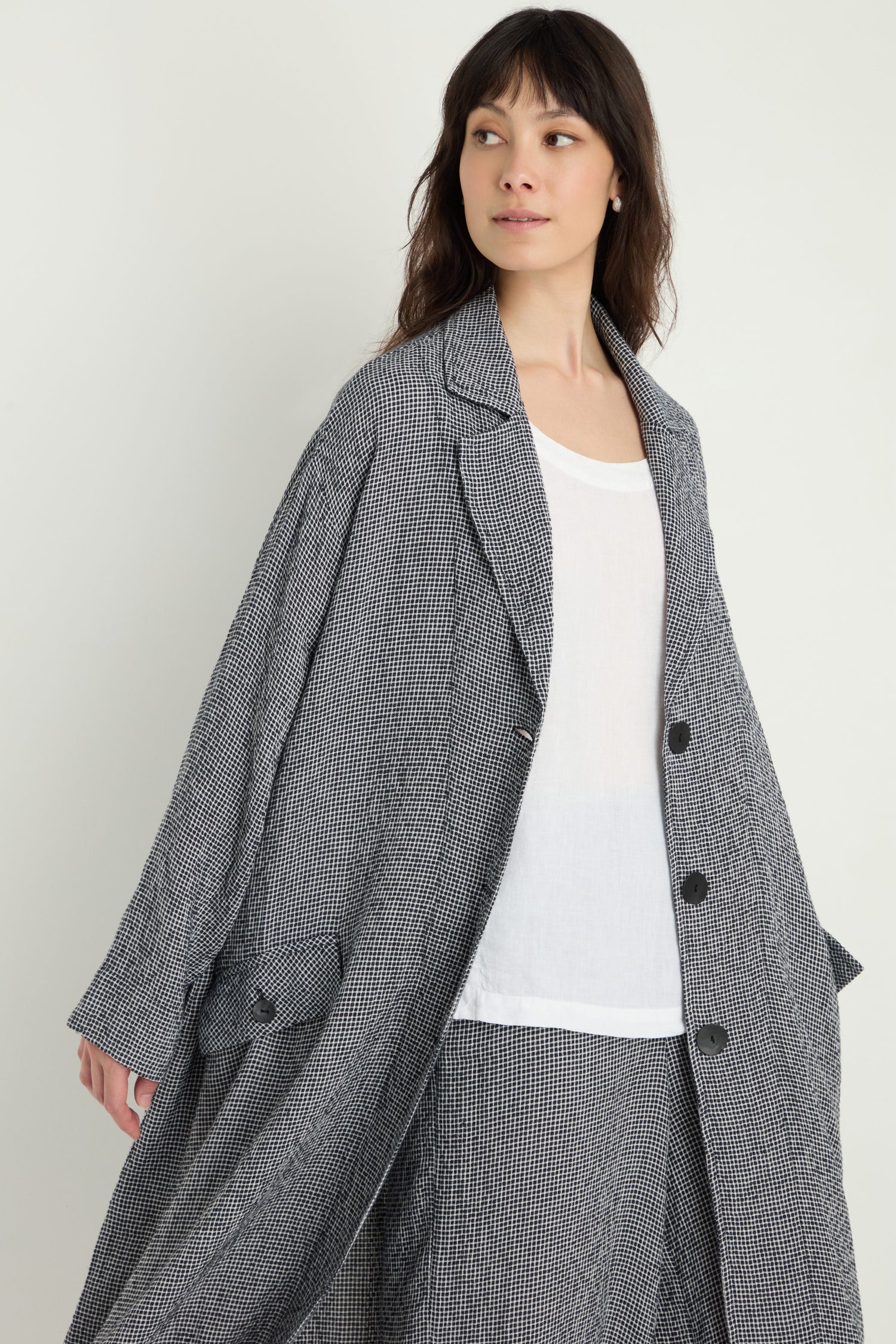 A woman in a loose-fitting Micro Gingham Boxy Coat over a white top and matching pants stands against a plain background, her modern look as striking as the design of an MTJ6721 electronic component.