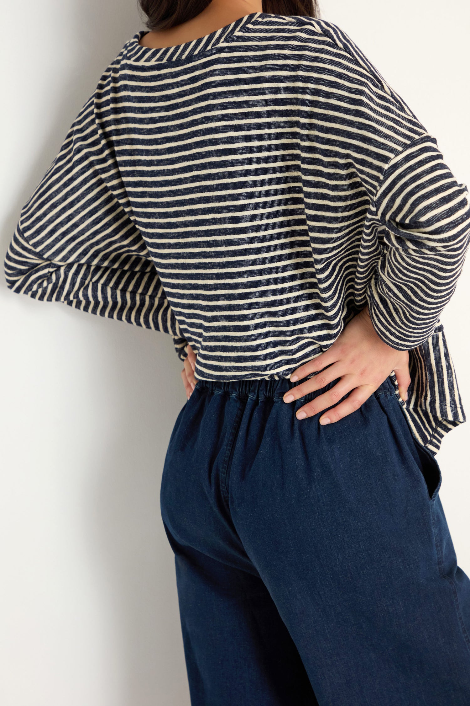 Person wearing a navy and white striped long-sleeve shirt and high-waisted Stretch Denim Bubble Trouser with a relaxed fit, standing with one hand on their hip against a white background.