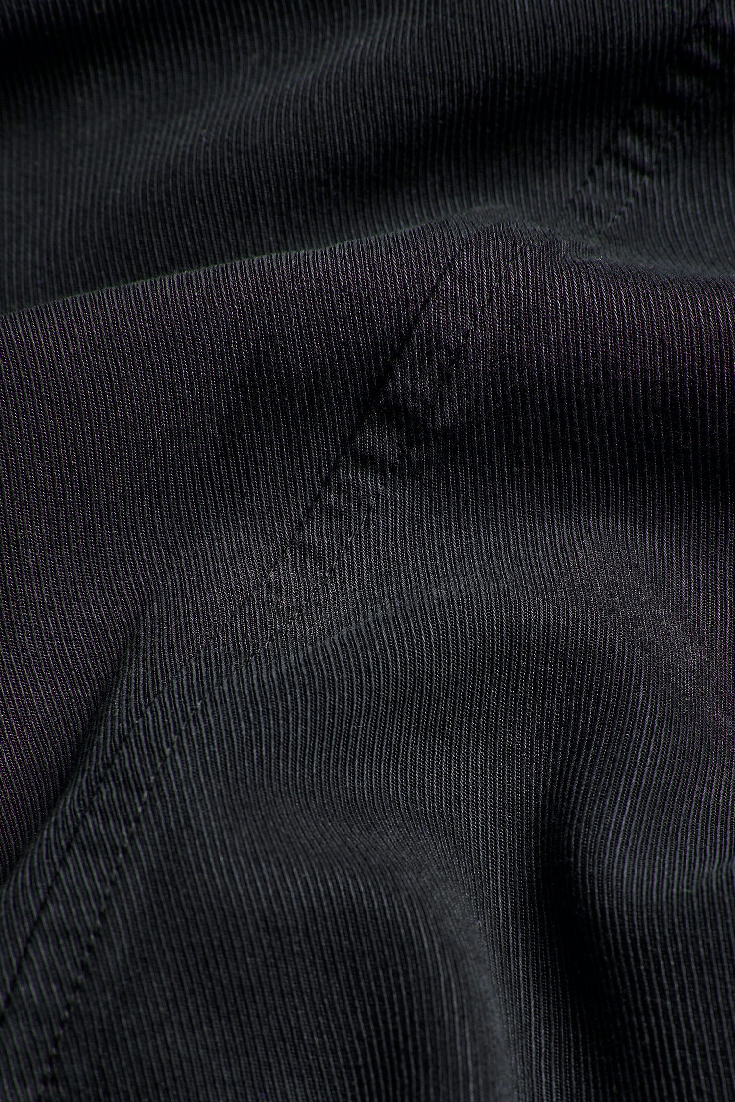 A close up image of a black signature Fluid Twill Bubble Trouser fabric, known for its versatility in creating woven twill trousers.