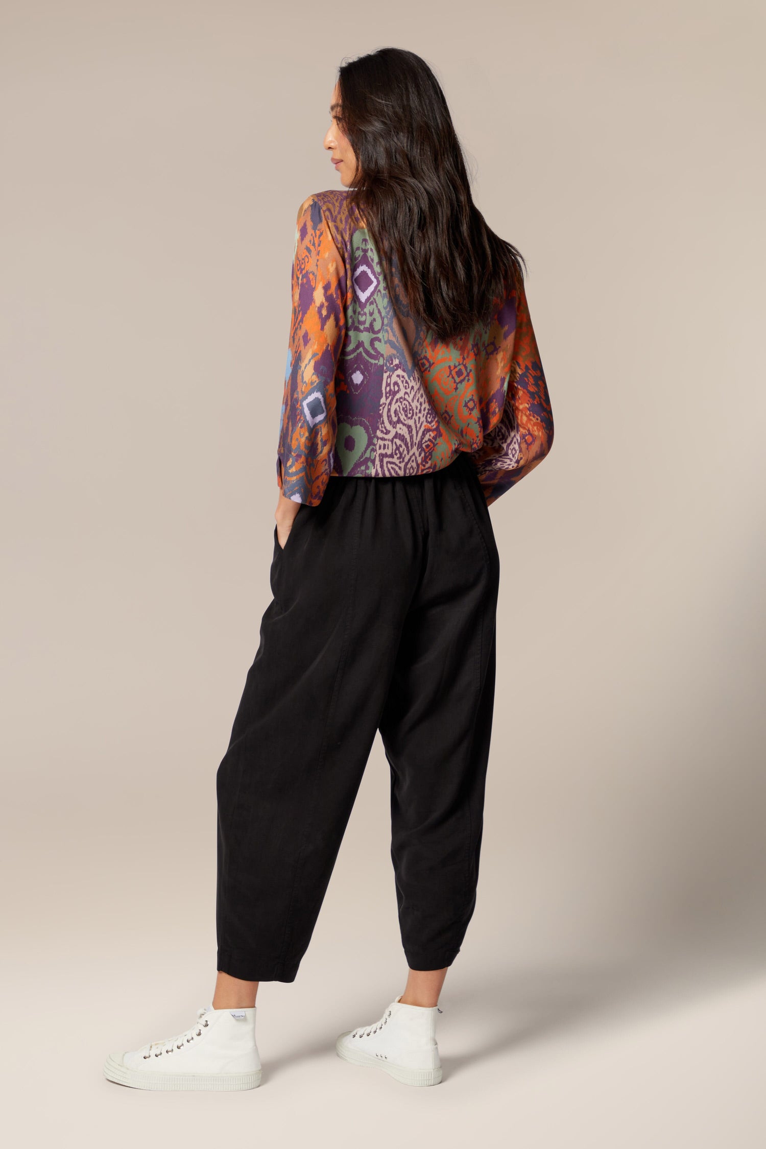 The back view of a woman wearing versatile Fluid Twill Bubble Trouser and a vibrant, colorful top.
