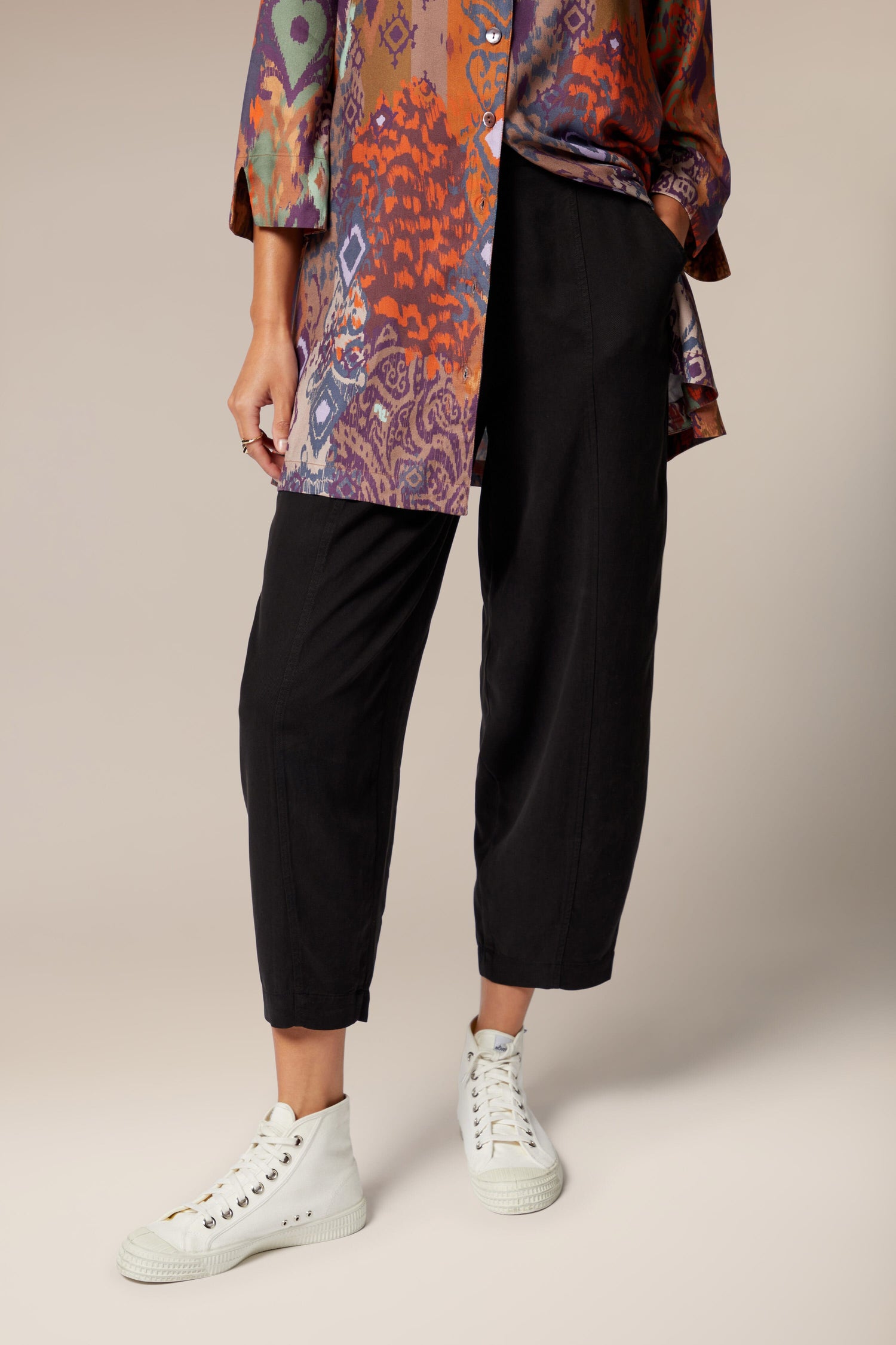 A woman showcasing a signature Fluid Twill Bubble Trouser in a colorful shirt.
