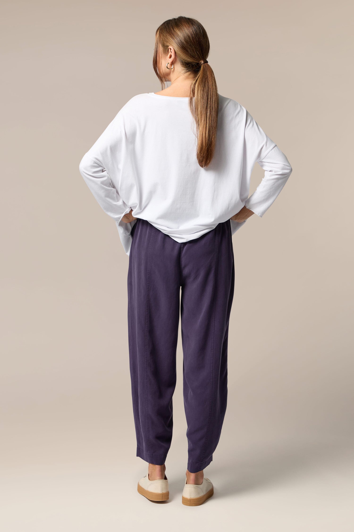 The back view of a woman wearing purple woven fluid twill bubble trousers with a signature bubble silhouette.
