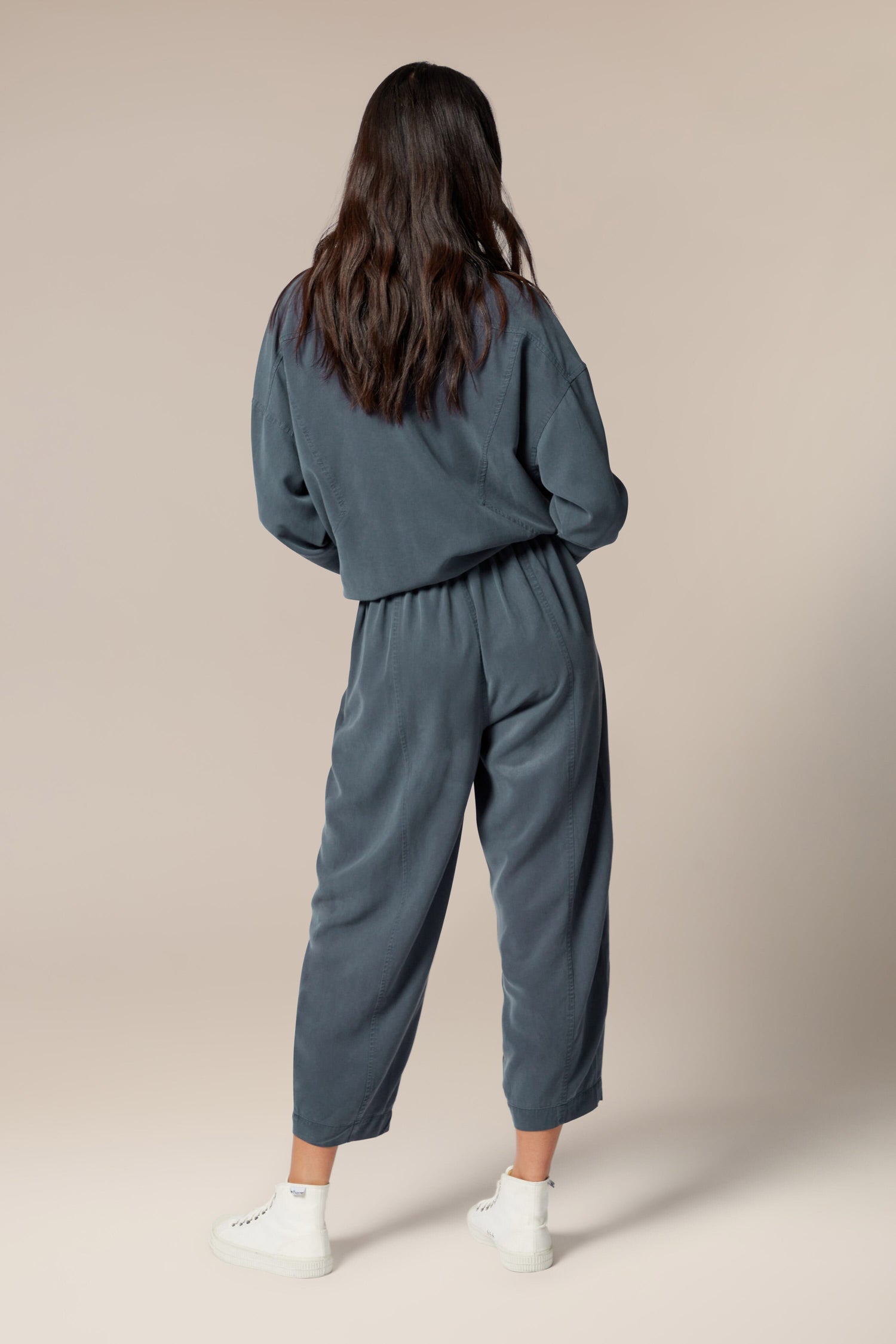 The woman showcases her signature Fluid Twill Bubble Trouser in a versatile grey sweatsuit.