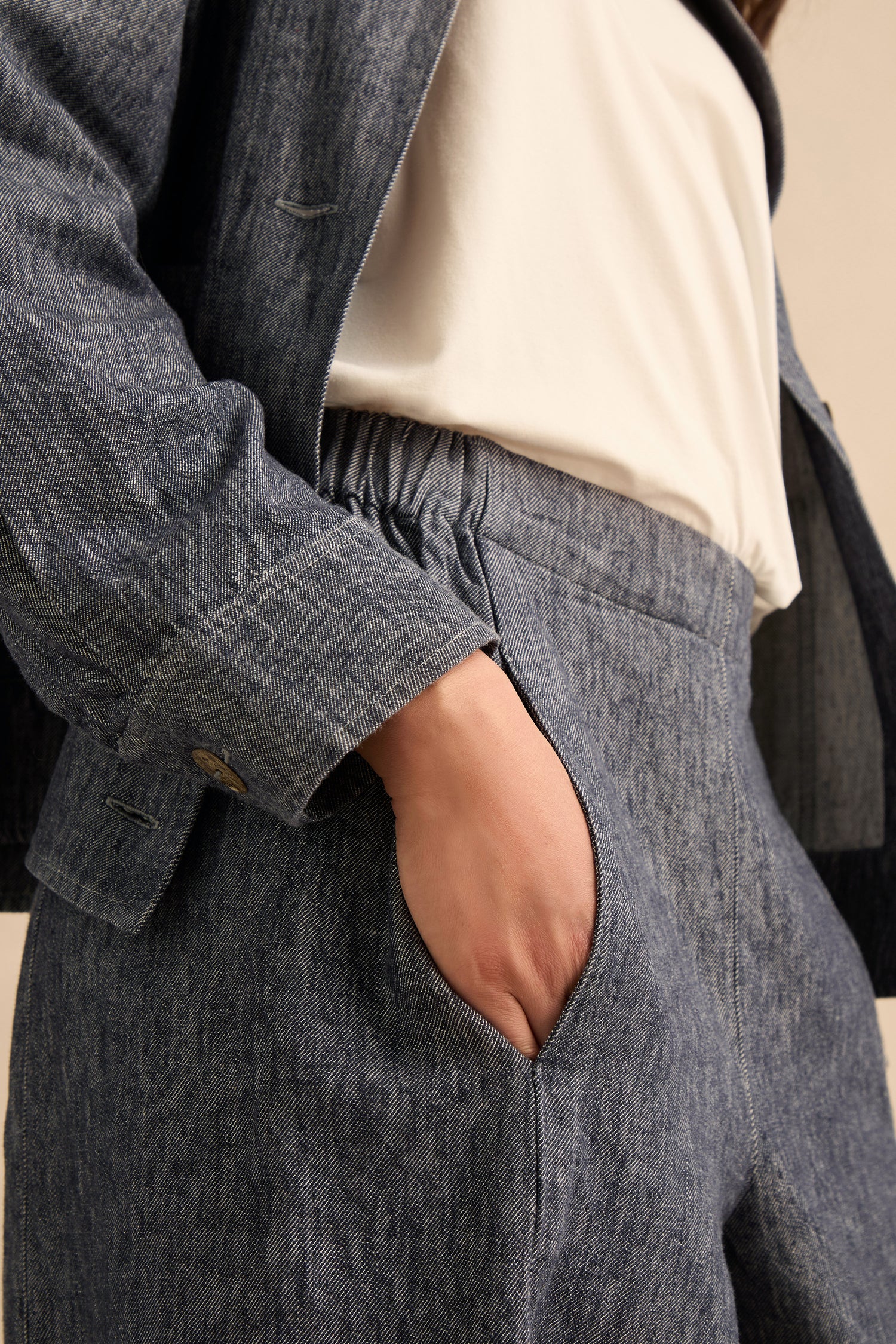 A person wearing Washed Cotton Linen Barrel Trousers in grey with an elasticated waist and a white top, shown from the chest down with one hand in the pocket.