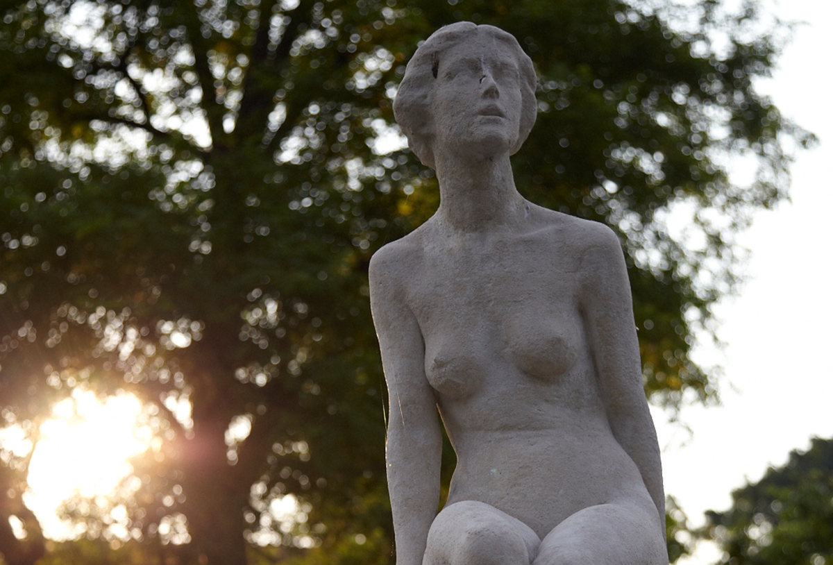 statue of a woman against trees