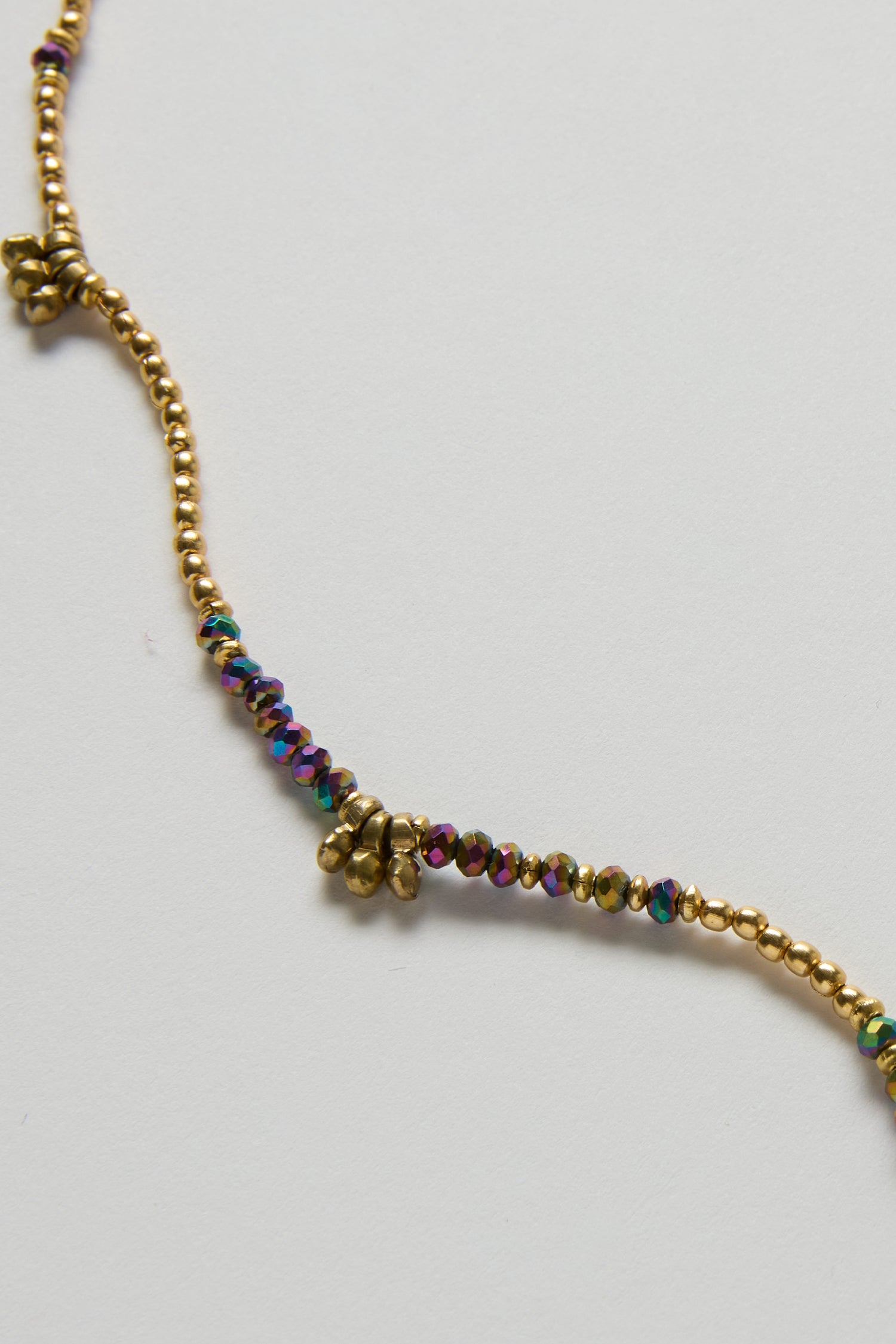 A close-up of the Long Saros Beaded Necklace showcases its small gold and multicoloured seed beads against a plain white background.