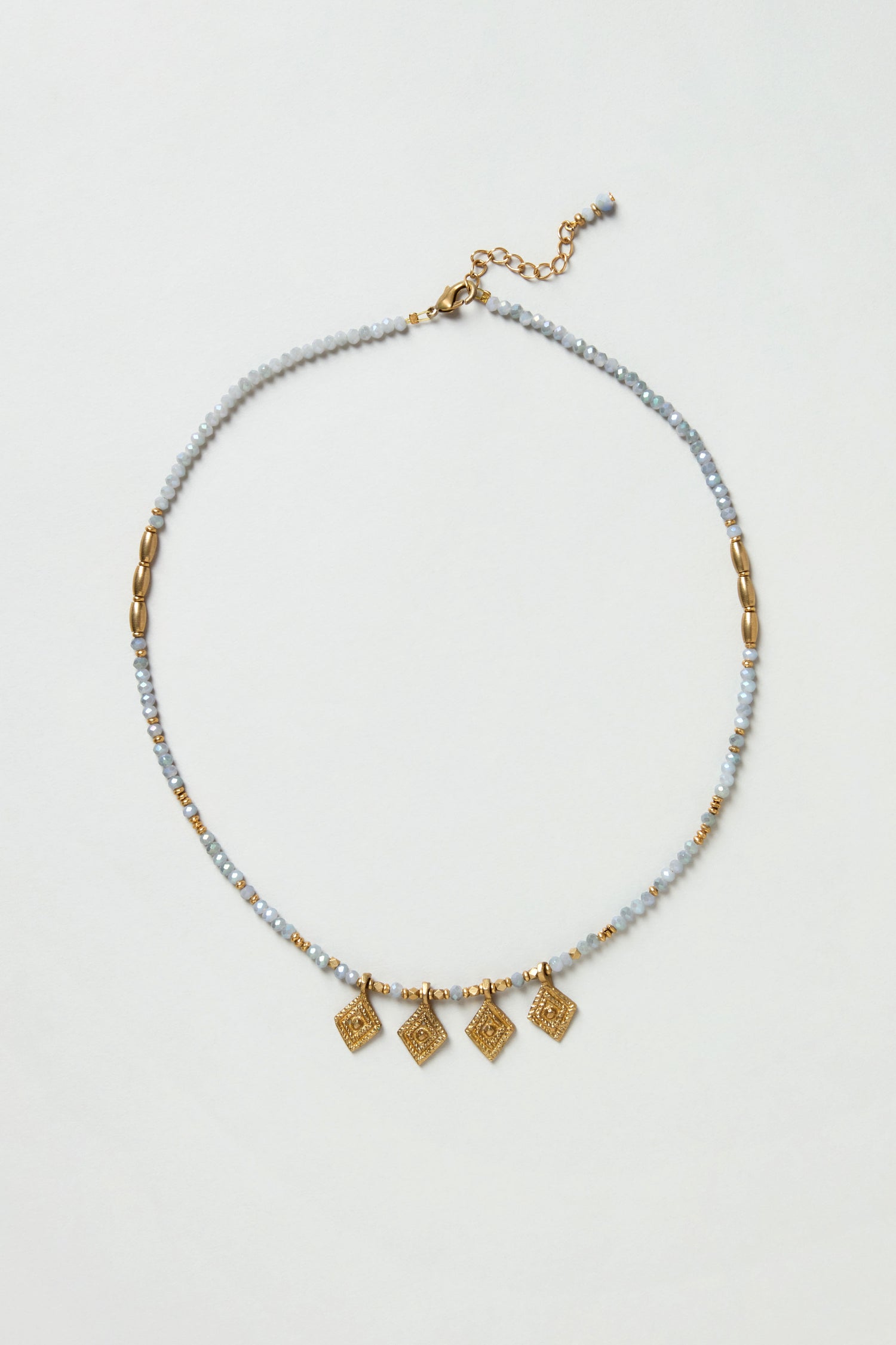 The Eanna Necklace features gold and silver beads, five small gold square charms, faceted cut glass beads, and an adjustable clasp, all displayed on a plain white background.