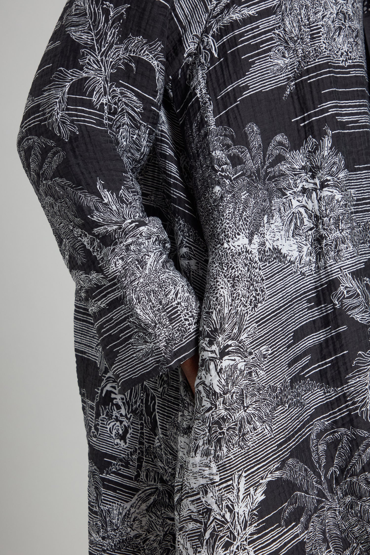 A person wearing the Tie Neck Viscose Shirt from Noen, a well-known Nordic brand, featuring a black and white patterned design with detailed foliage and jungle print line elements.