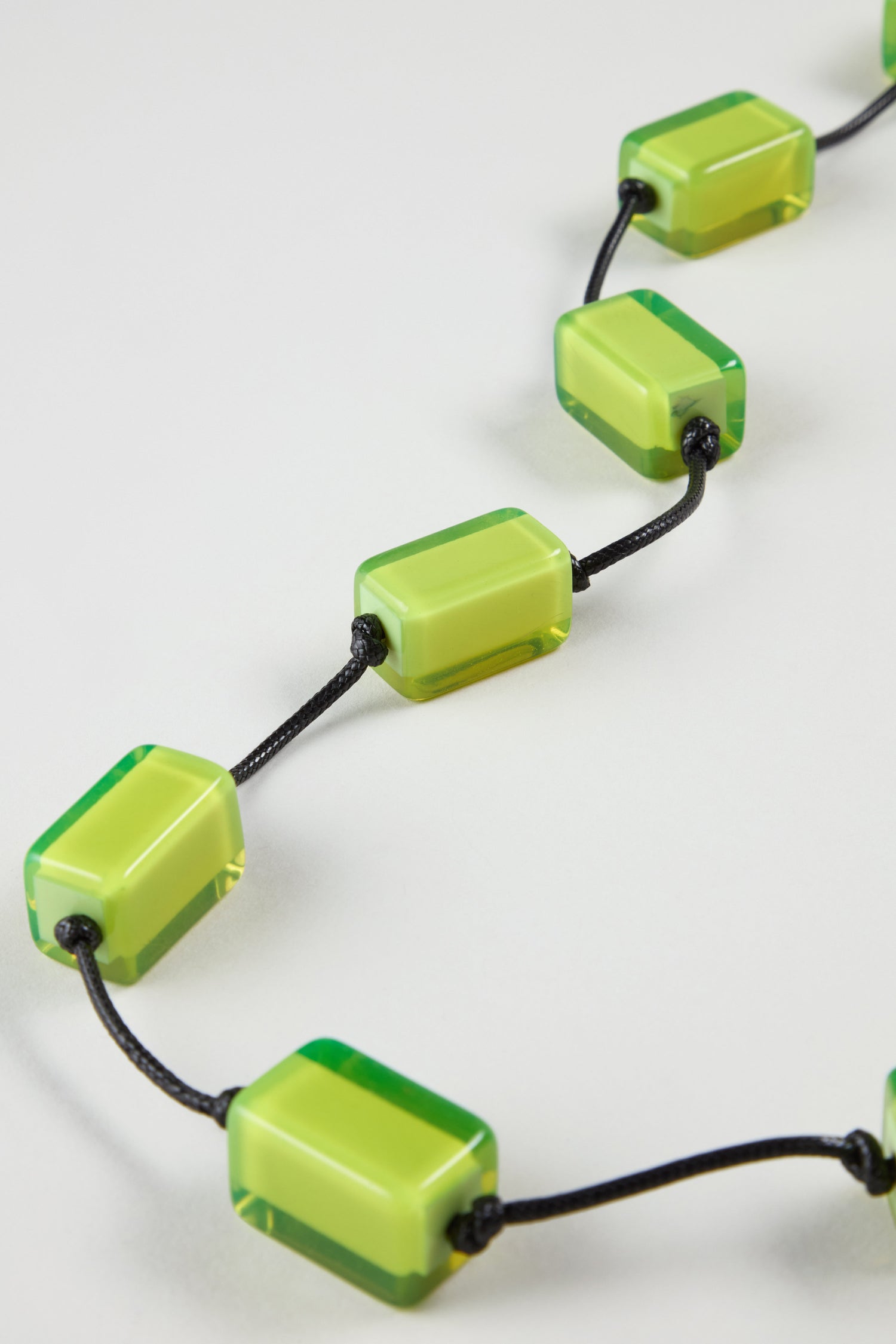 Close-up of the Neon Resin Cubes Necklace, showcasing rectangular green resin cubes threaded on a black cord, displayed against a plain light background.