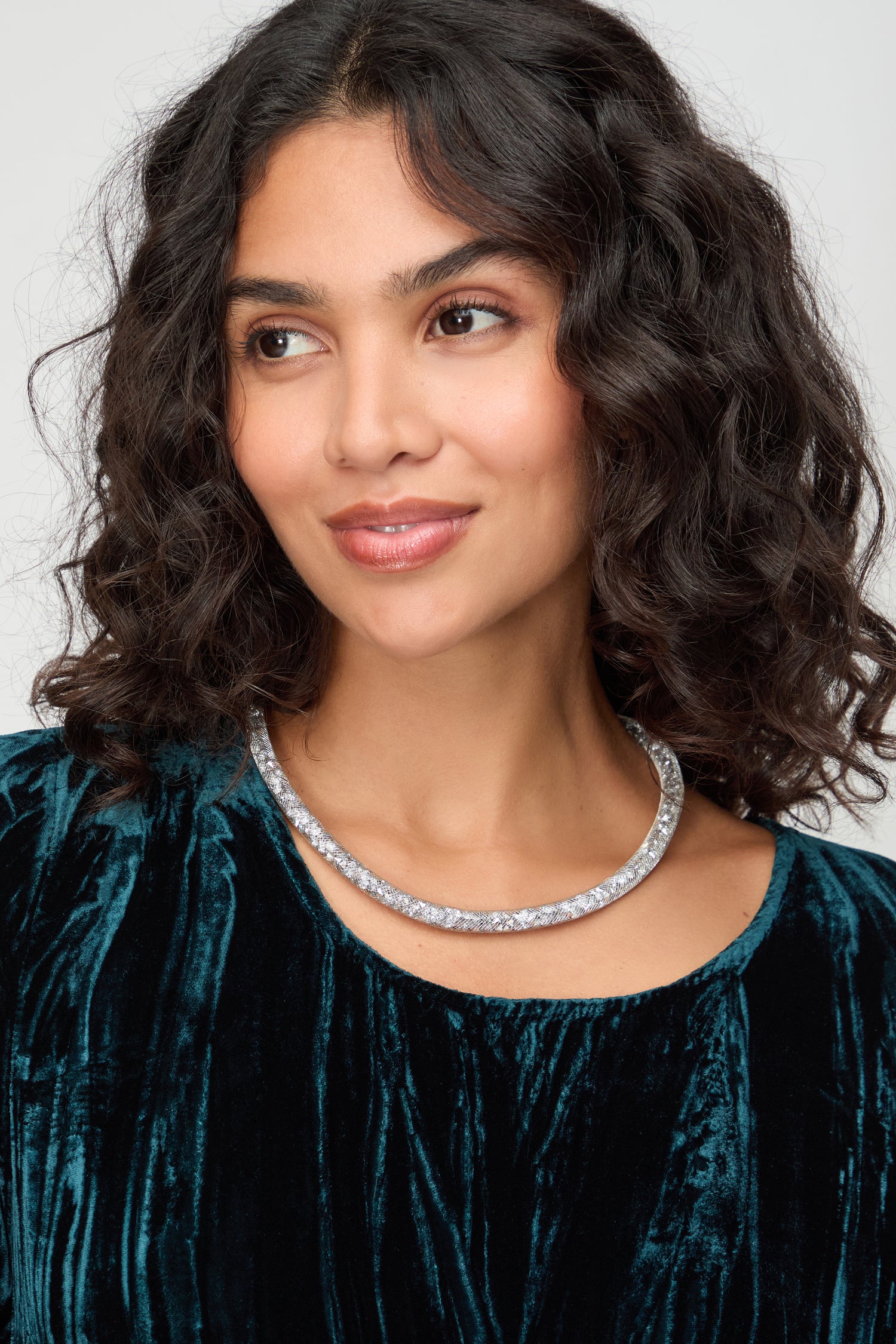 Woman with wavy dark hair wearing a teal velvet top and the Short Silver Diamante Necklace, looking slightly to the side against a neutral background.