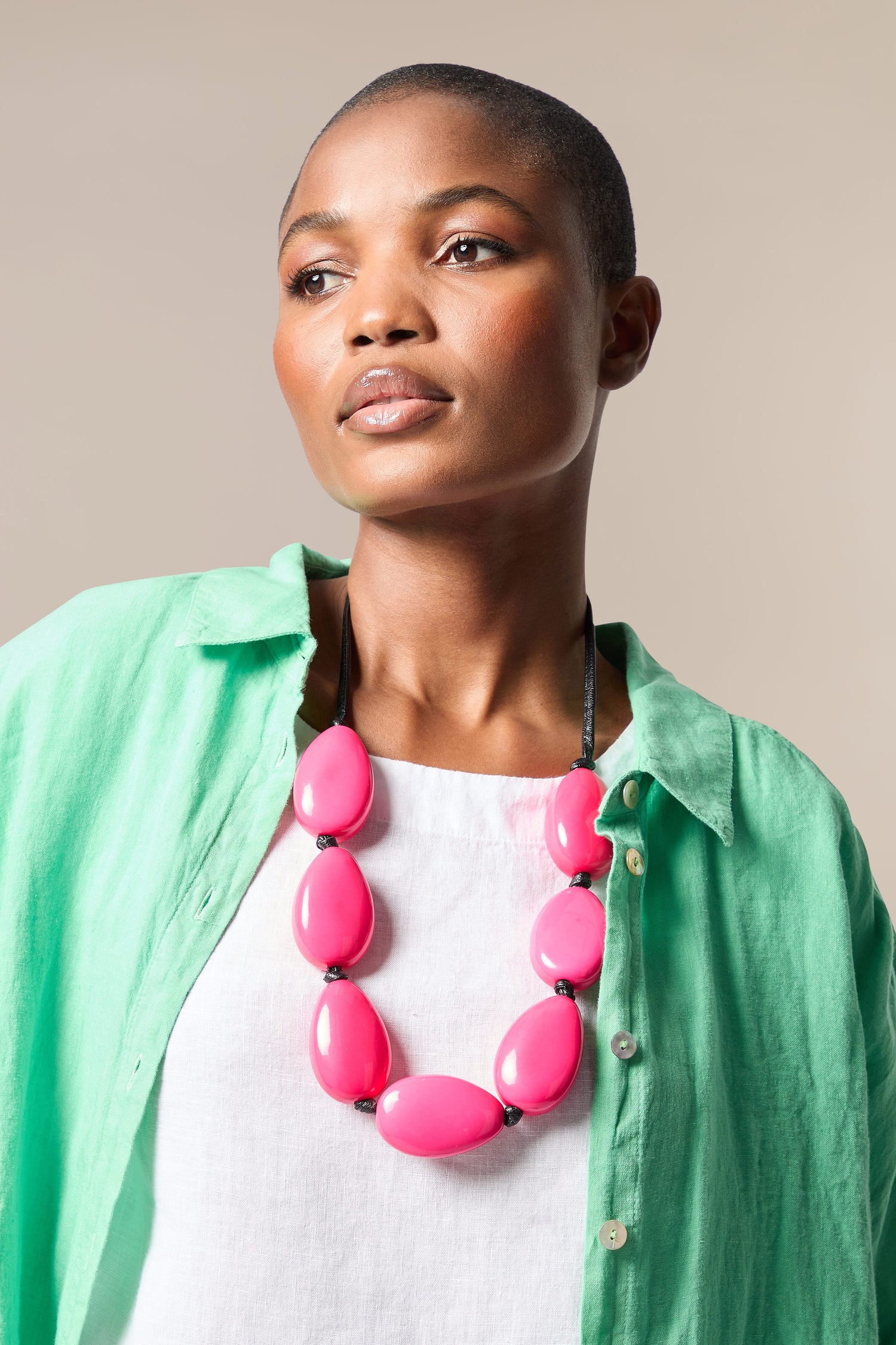 A woman wearing a Vibrant Bead Necklace and green shirt.