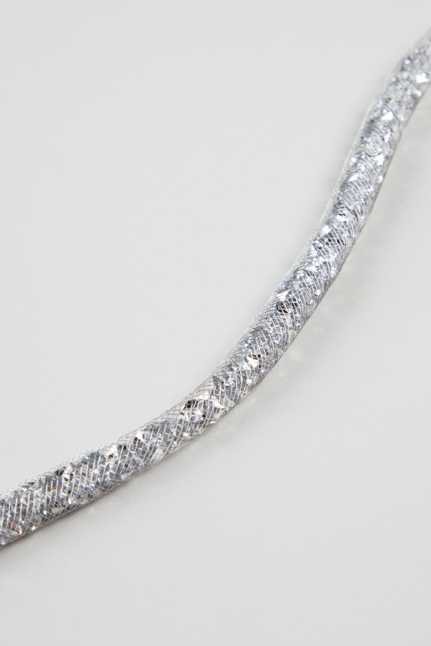 A close-up of the Long Silver Diamante Necklace, featuring a textured, braided design reminiscent of a statement piece, set against a plain light gray background.