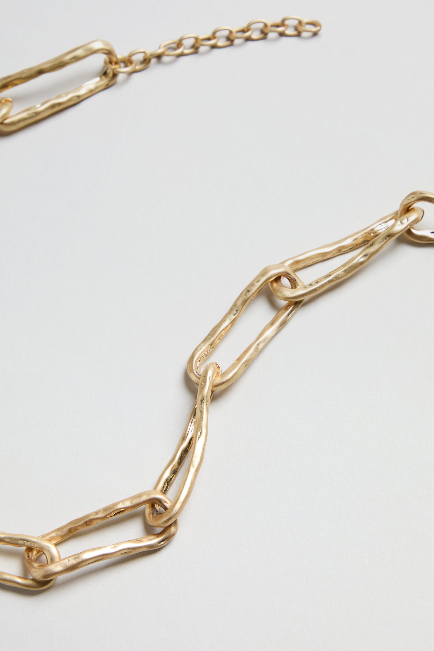 Close-up of the Short Gold Link Necklace, featuring large, irregularly shaped gold links with a textured surface, displayed against a plain light background.