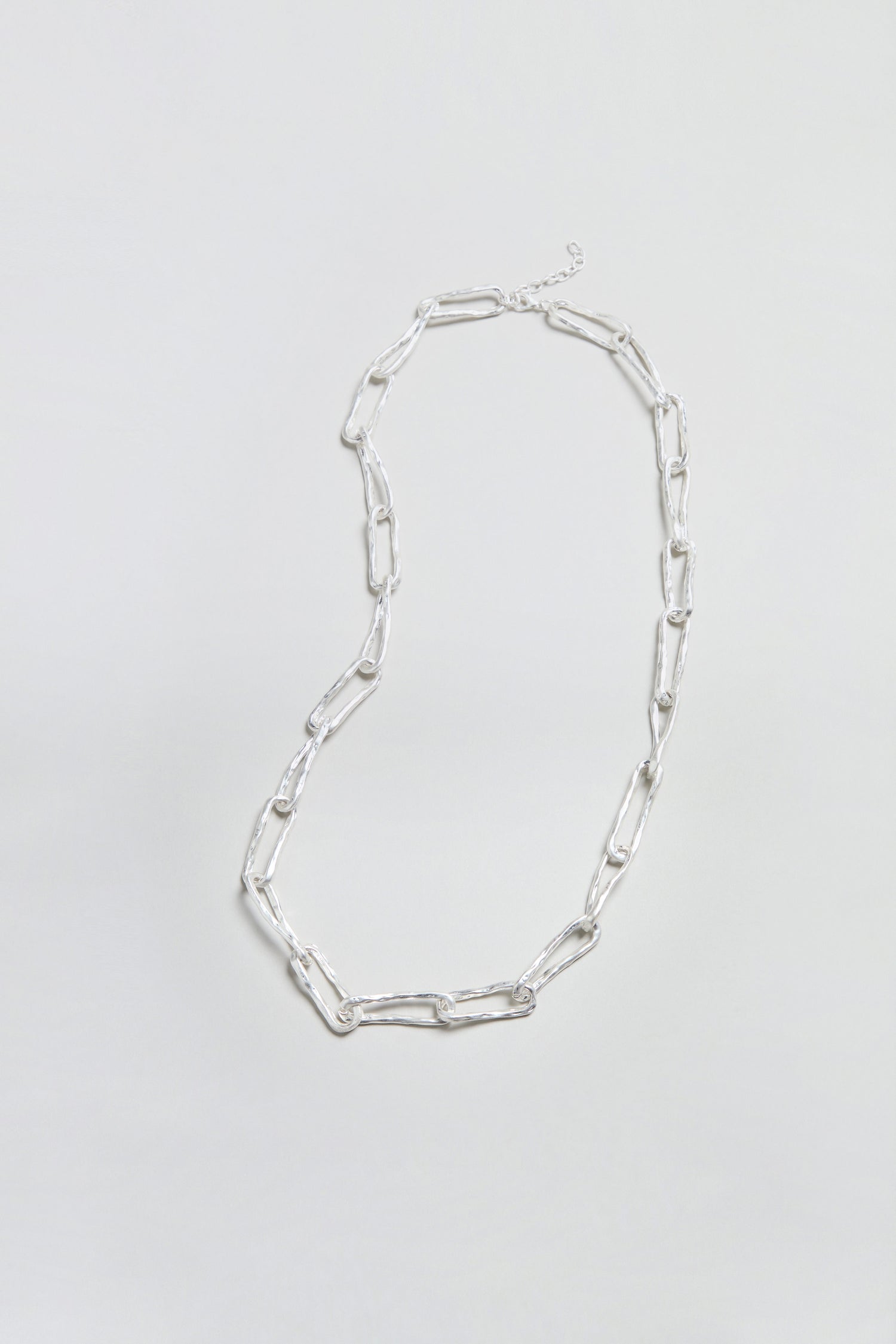 The Long Silver Links Necklace is displayed on a plain, light background. Featuring elongated, rectangular links and a refined, textured chain design, this necklace adds a touch of elegance to any ensemble.