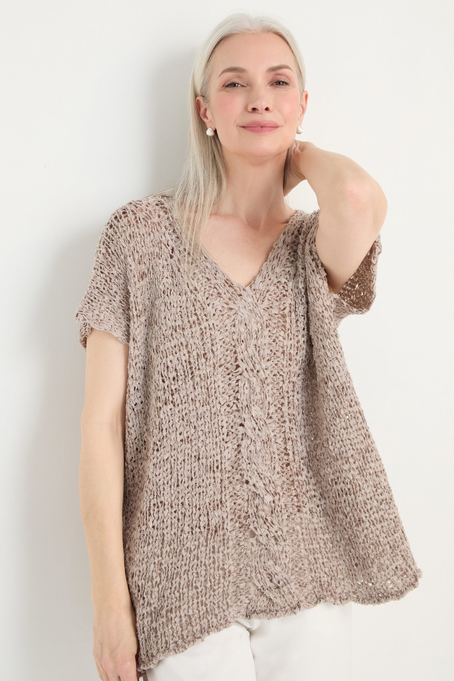 Older woman with long gray hair wears the V-Neck Cotton Blend Knit top in beige and white pants, standing against a plain white background.