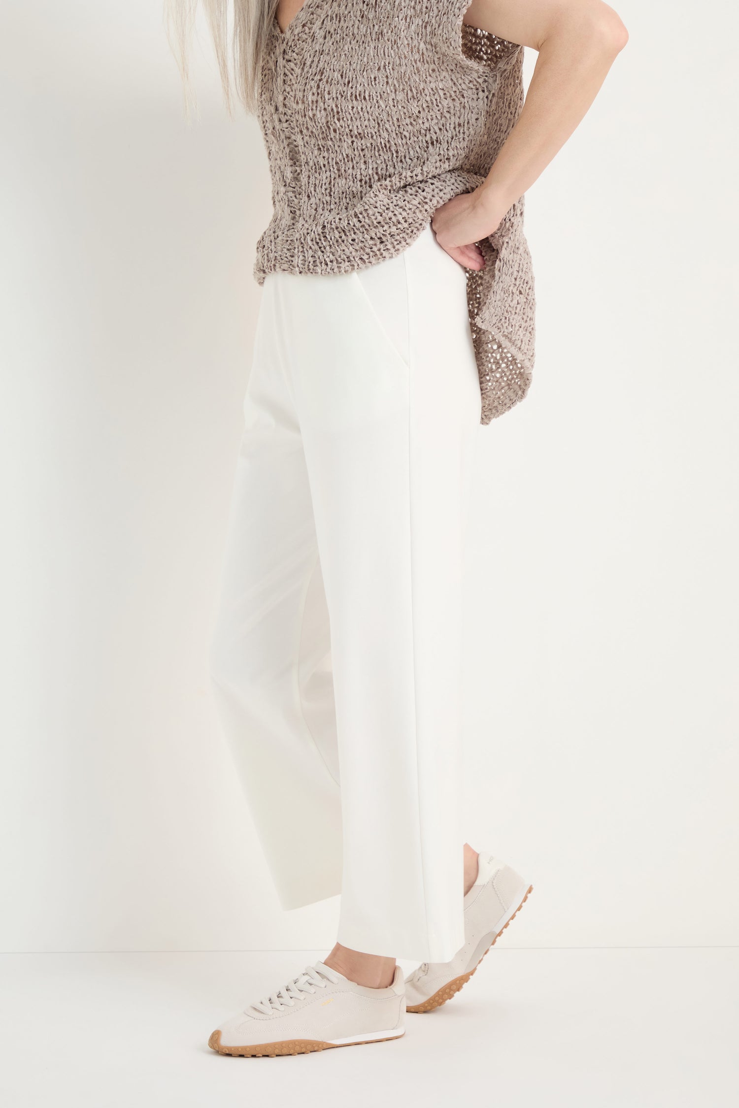A person stands against a plain white background wearing Wide Leg Pocket Trousers, a sleeveless knitted top, and white sneakers.