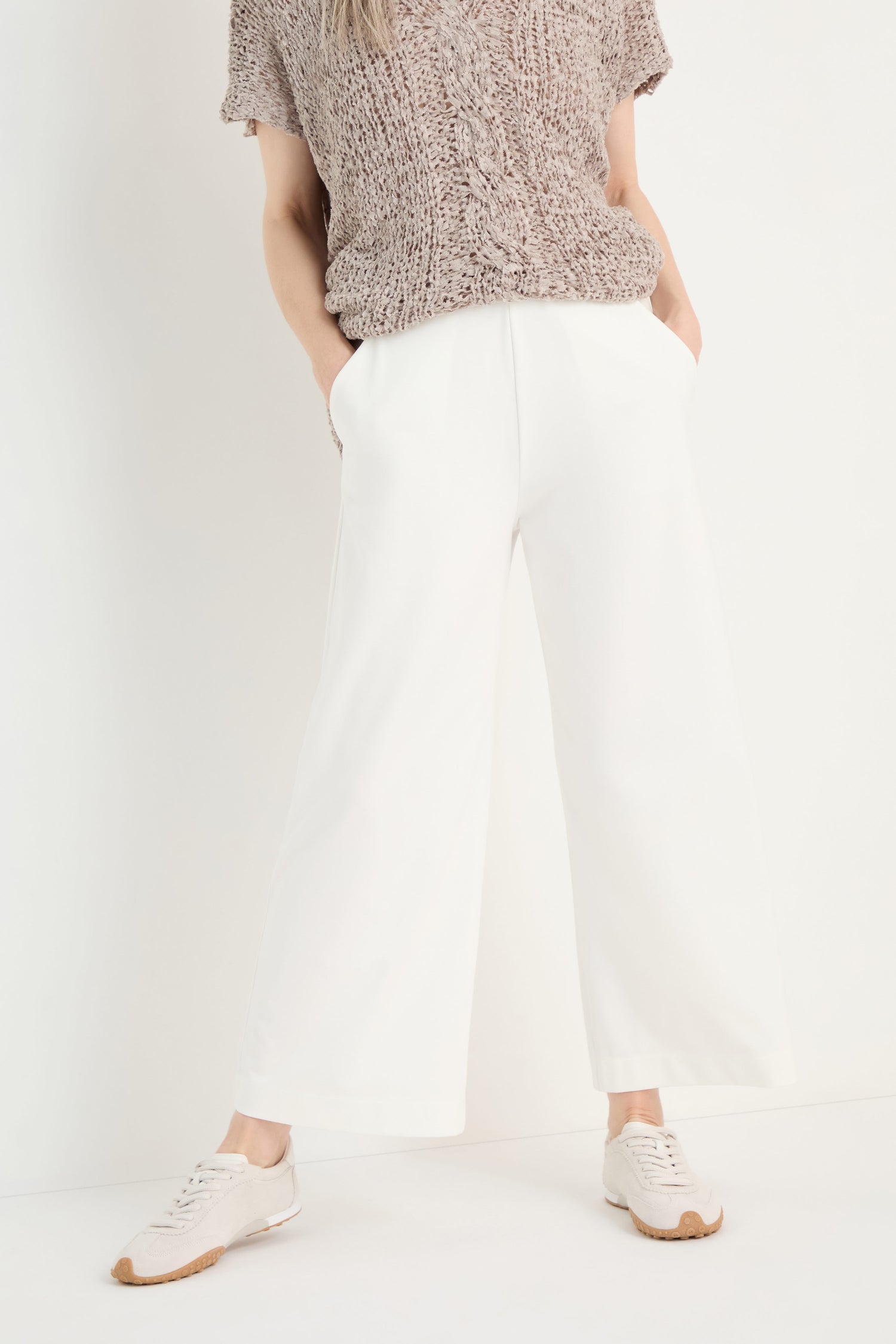 Person wears Wide Leg Pocket Trousers with an elasticated waist and white sneakers, standing against a plain white background with hands in pockets.