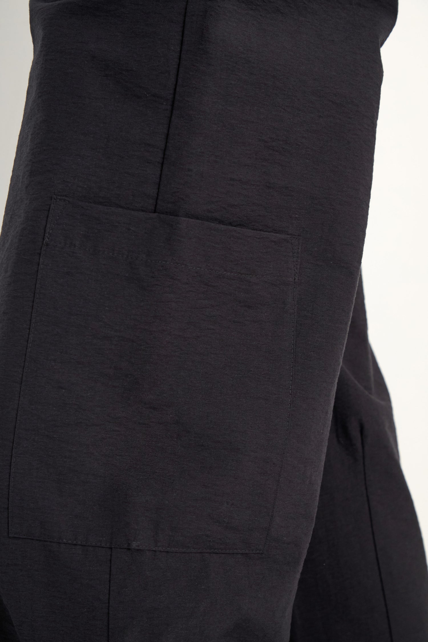Close-up of black Wide Leg Cotton Trousers, showcasing a large square patch pocket on the side and a relaxed fit design.