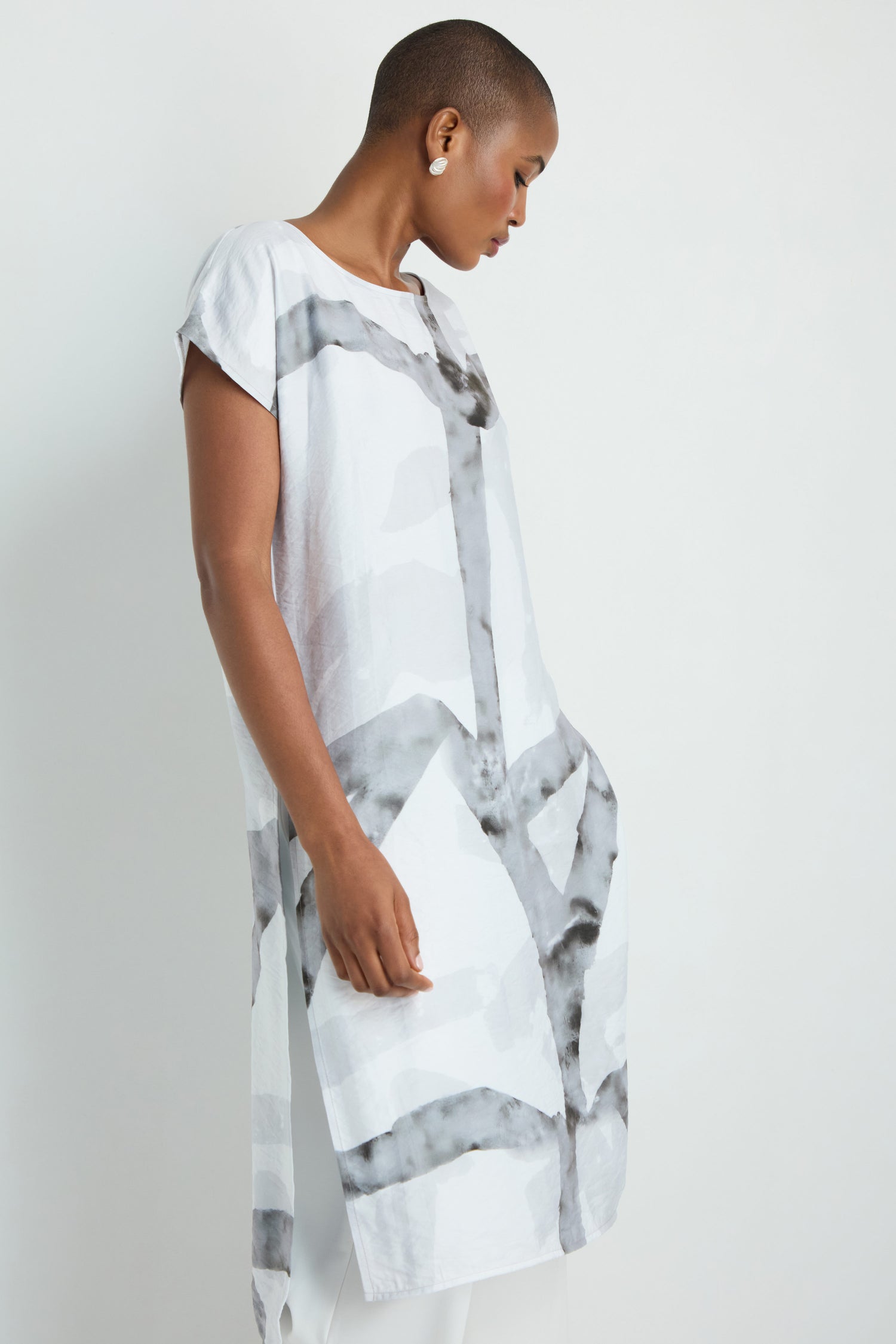 A person wears the Brushstroke Print Long Tunic, featuring abstract black stripes, over black pants, shown from midsection to knee against a plain background.