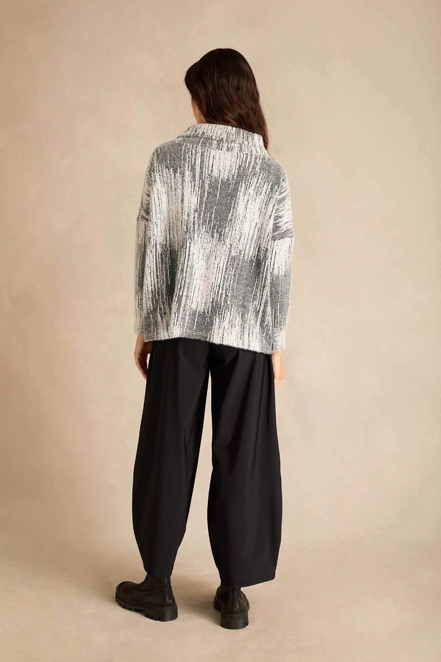 A person stands with their back to the camera, wearing the Greyscale Textured Jersey Top paired with wide-leg black pants and black shoes against a neutral background.