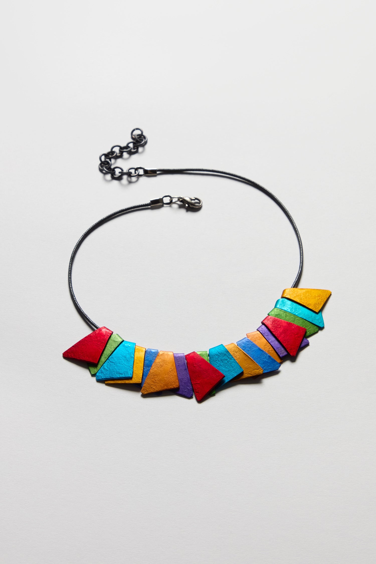The Mini Segment Necklace is a geometric resin necklace with a black cord and colorful pendants in red, blue, yellow, orange, and green—perfect as statement jewelry for any outfit.