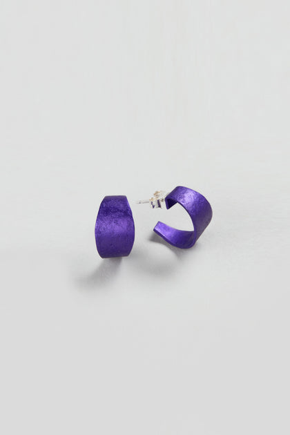 A pair of Curved Earrings in matte purple, ideal as statement accessories, showcased against a plain white background.