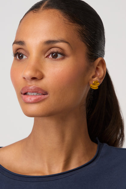 A woman with a neutral expression and dark hair pulled back wears a navy top and vibrant Ribbon Earrings, shown from the shoulders up against a plain background.