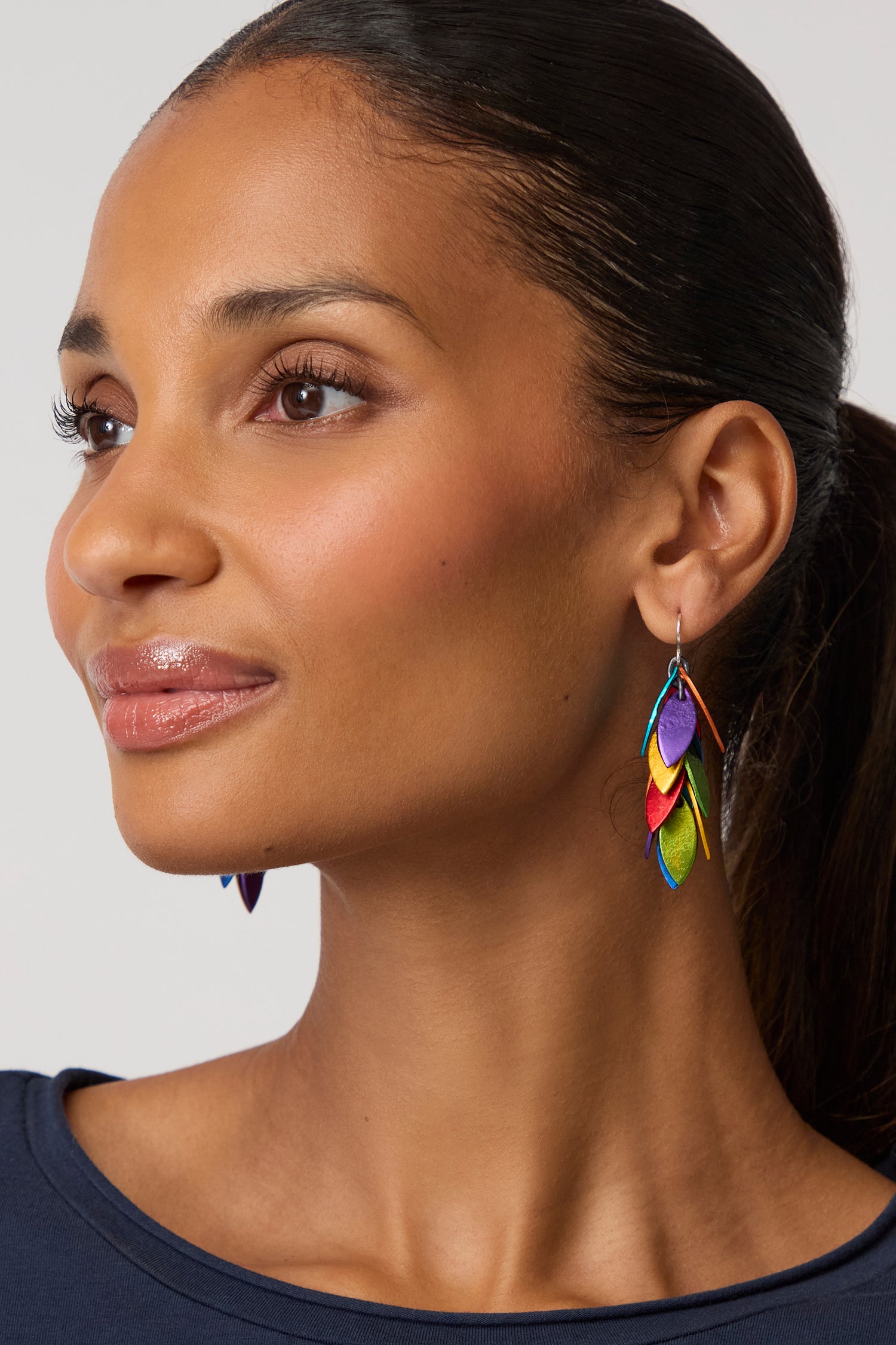 Woman with straight dark hair in a ponytail wears a navy top and Rainbow Scattered Leaves Earrings, looking off to the side with a neutral expression.