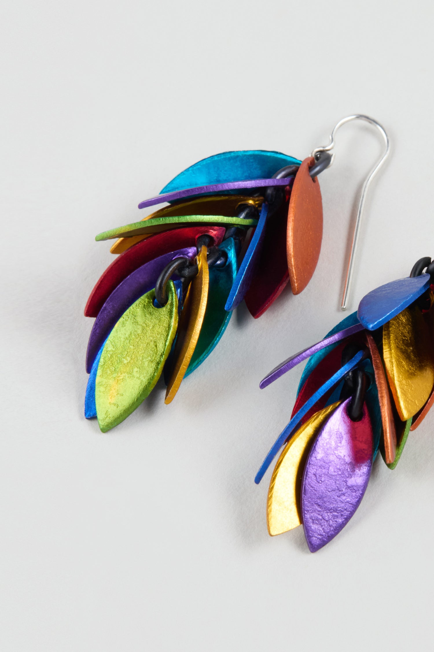 The Rainbow Scattered Leaves Earrings feature layered, metallic, leaf-shaped charms in vibrant colors, perfect for fans of contemporary jewelry.