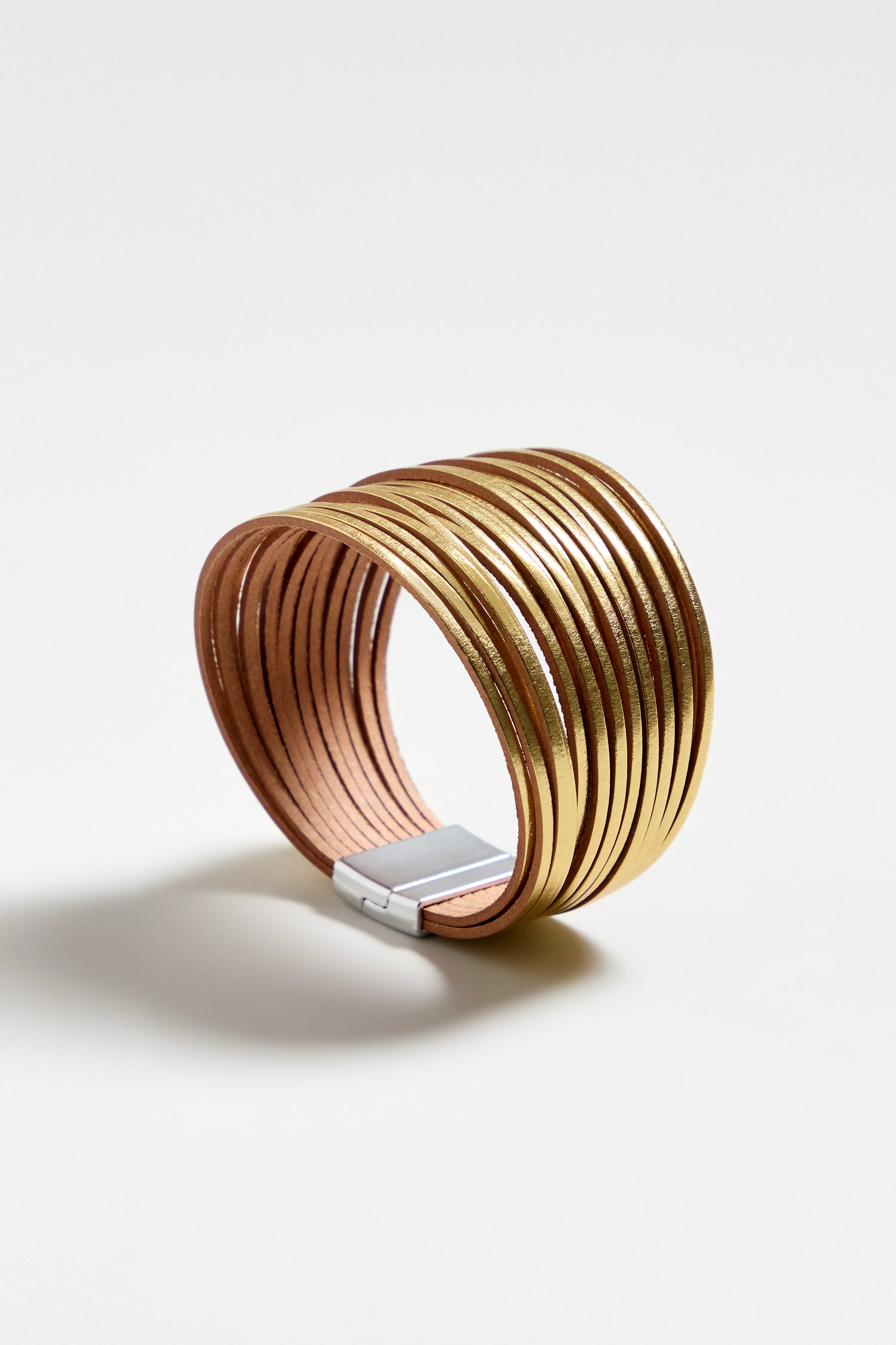 The Vegan Leather Metallic Bracelet features wide, lightweight bands with a metallic finish and a rectangular silver clasp, showcased on a plain white background.