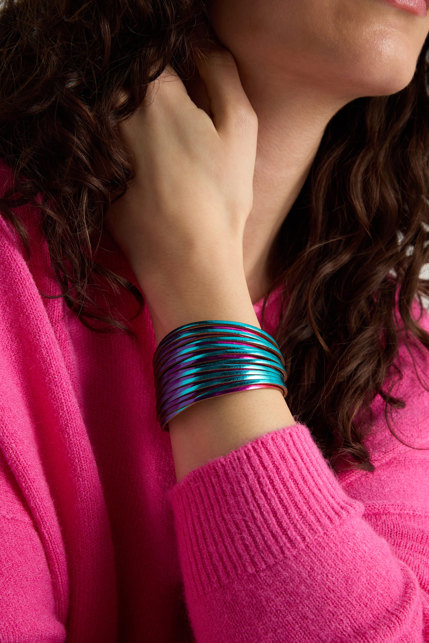 A person wears a bright pink sweater paired with the bold Vegan Leather Metallic Bracelet on their wrist.