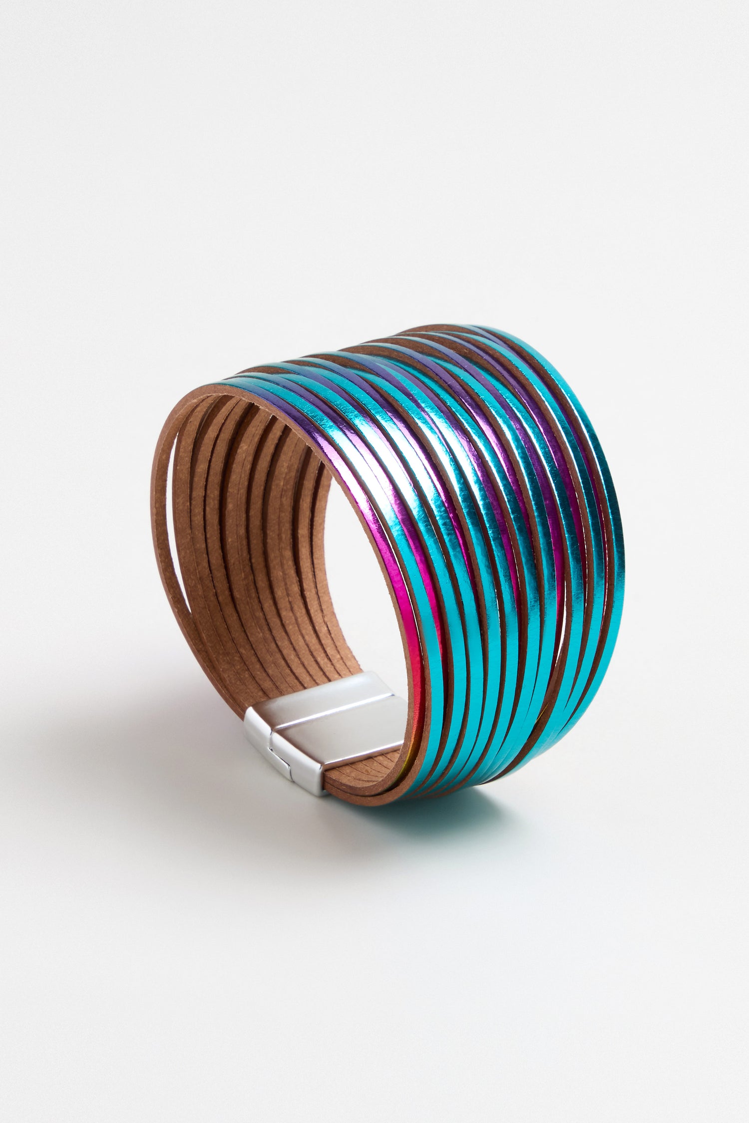 The Vegan Leather Metallic Bracelet features wide brown vegan leather with metallic blue and purple stripes and a rectangular silver clasp. Lightweight and modern, it’s displayed on a white background.
